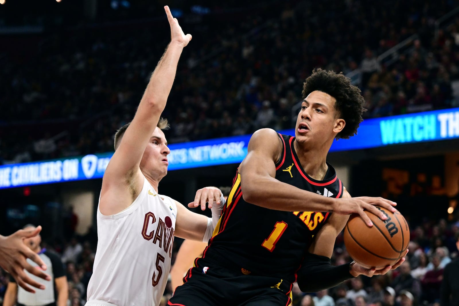 Atlanta Hawks forward Jalen Johnson looks to pass against Cleveland Cavaliers guard Sam Merrill in the first half of an NBA basketball game, Wednesday, Nov. 23, 2024, in Cleveland. (AP Photo/David Dermer)