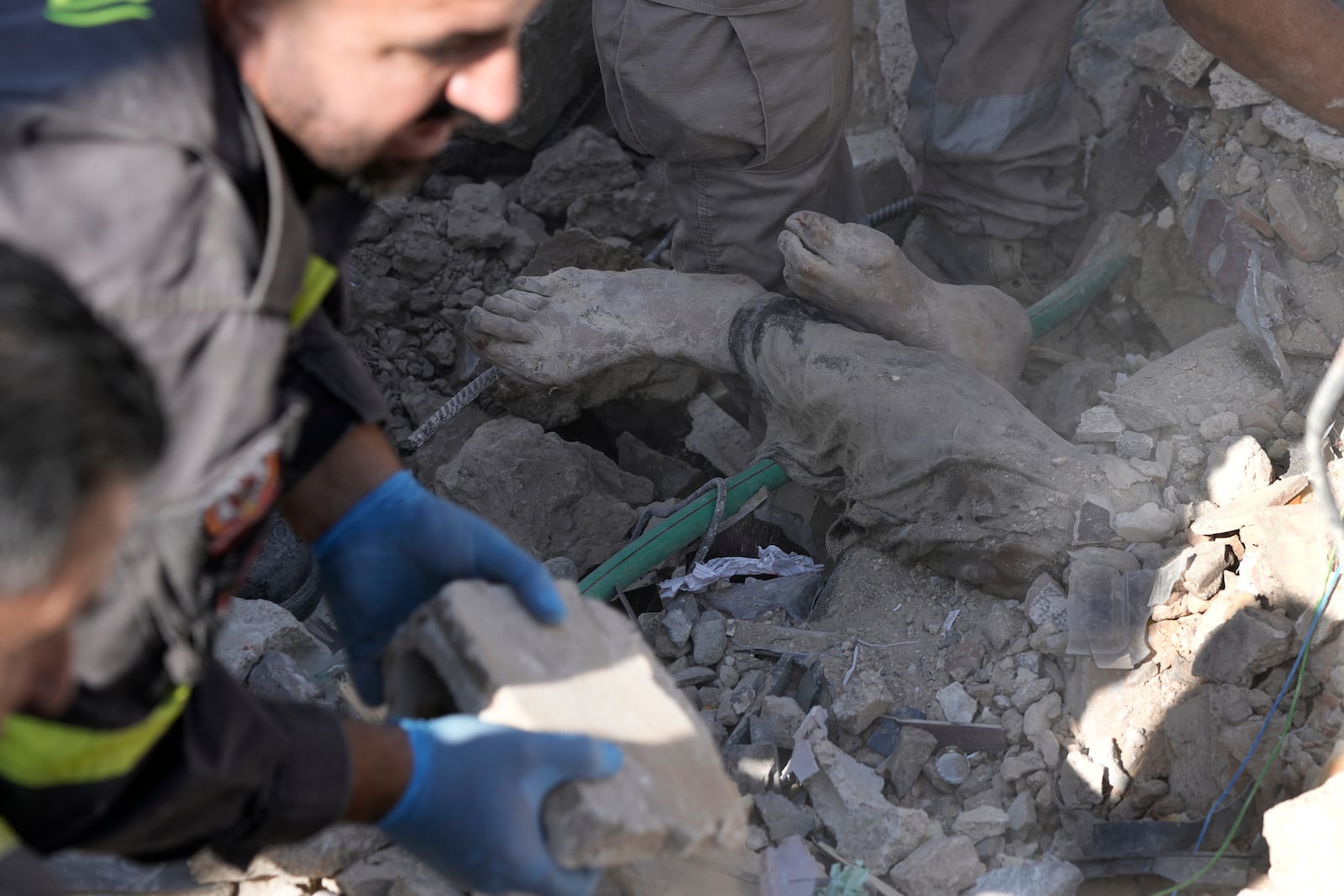 EDS NOTE: GRAPHIC CONTENT - Rescue workers clear the rubble to retrieve a body at the site of a destroyed building hit in an Israeli airstrike on Tuesday night, in Sarafand, southern Lebanon, Wednesday, Oct. 30, 2024. (AP Photo/Bilal Hussein)