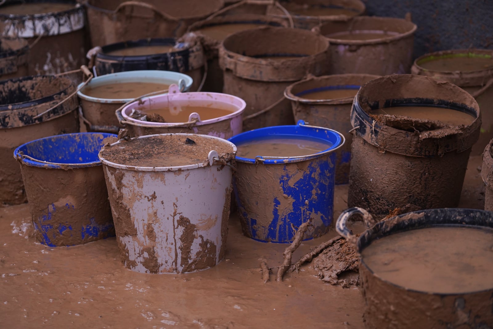 Buckets of collected mud and water sit in the street after floods on the outskirts of Valencia, Spain, Monday, Nov. 4, 2024. (AP Photo/Alberto Saiz)