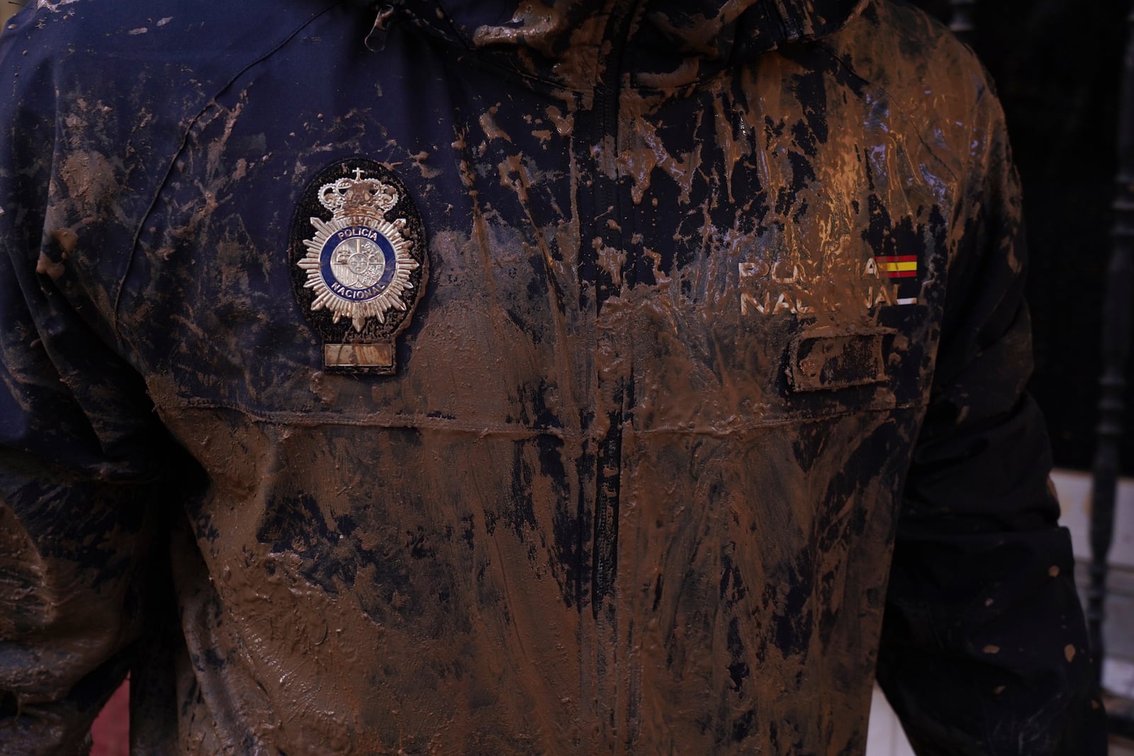 A Police officer's mud covered uniform and badge is pictured as he prepares to continue work on the clean up operation after flooding in Massanassa on the outskirts of Valencia, Spain, Wednesday, Nov. 6, 2024. (AP Photo/Alberto Saiz)