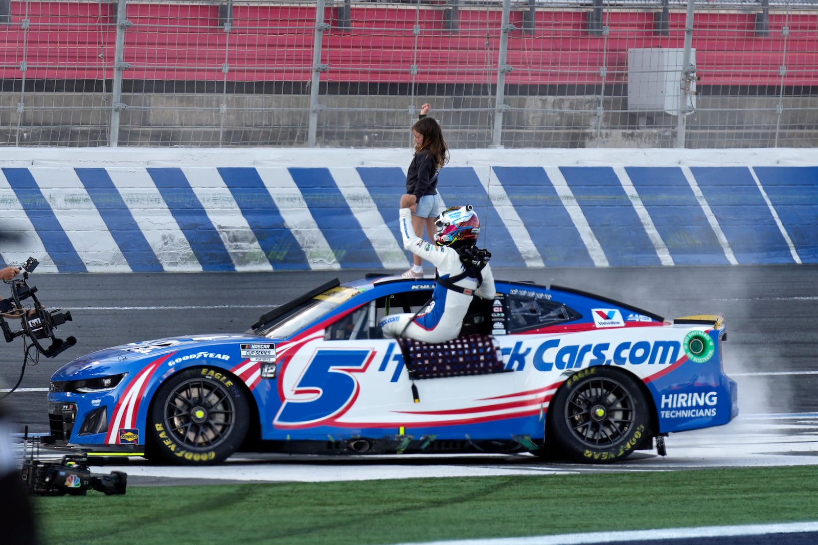 Kyle Larson celebrates with his daughter Audrey Larson, 6, top, after winning a NASCAR Cup Series auto race at Charlotte Motor Speedway in Concord, N.C., Sunday, Oct. 13, 2024. (AP Photo/Chuck Burton)