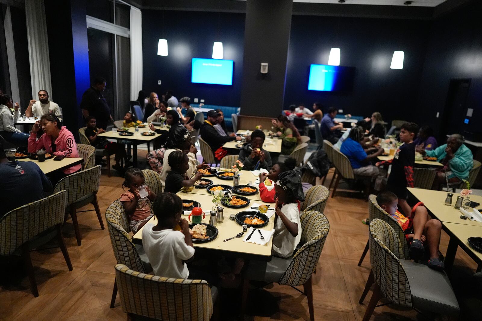 Off-duty staff members and their families, who were invited to come stay with them in hotel rooms as they worked through Hurricane Milton, eat dinner as the storm makes landfall on Florida's Gulf Coast, at Hyatt Place Tampa Downtown hotel in Tampa, Fla., Wednesday, Oct. 9, 2024. (AP Photo/Rebecca Blackwell)