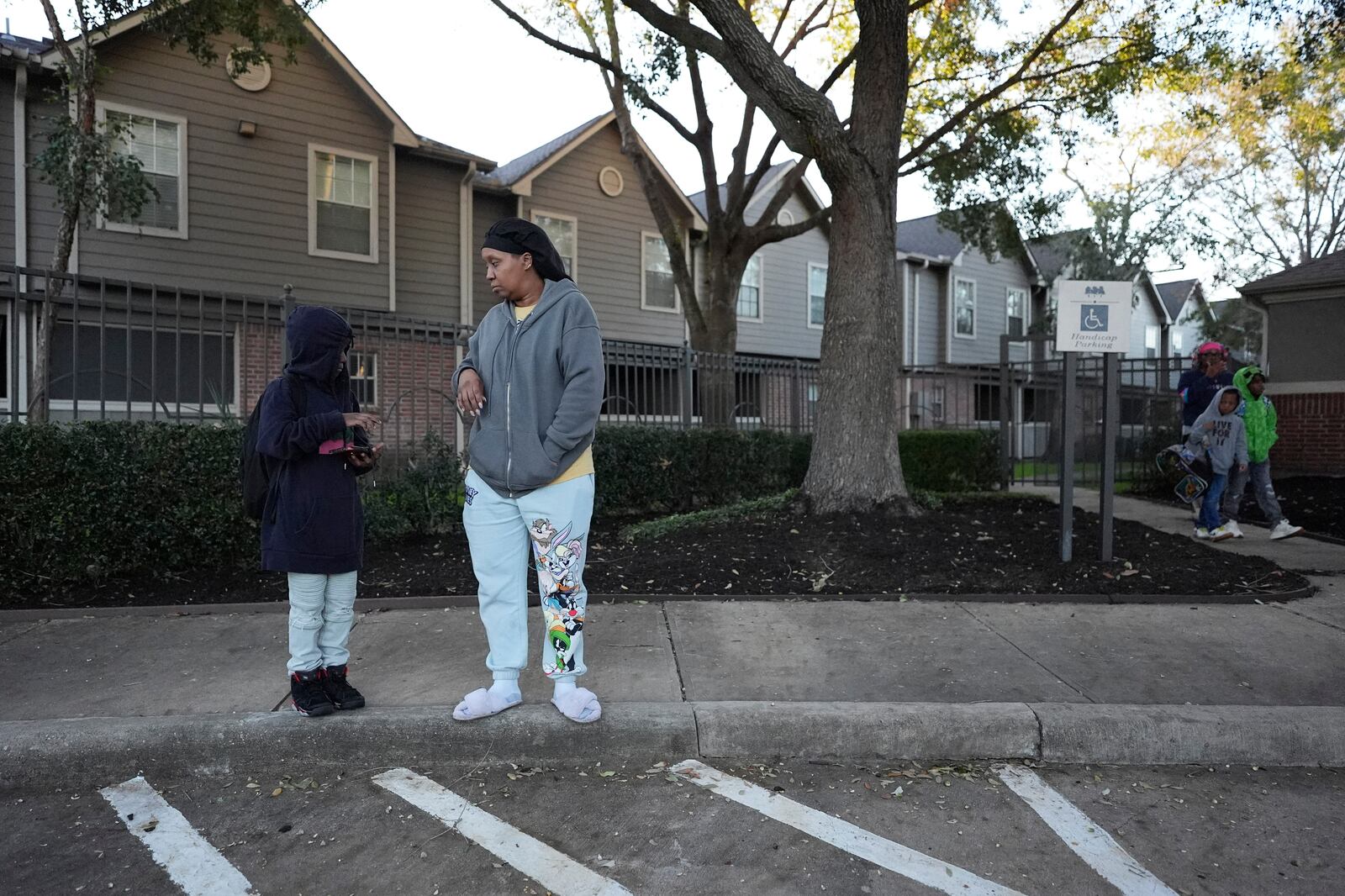 TiAnna Yeldell, right, stands with her son Ivan, 8, as he waits for the school bus to arrive, Friday, Nov. 15, 2024, in Missouri City, Texas. (AP Photo/Eric Gay)