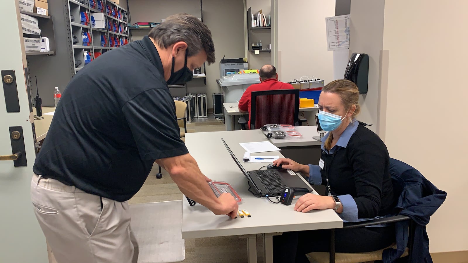 Montgomery County Board of Elections Deputy Director Steve Harsman hands off USB cards containing vote tallies to another elections worker.