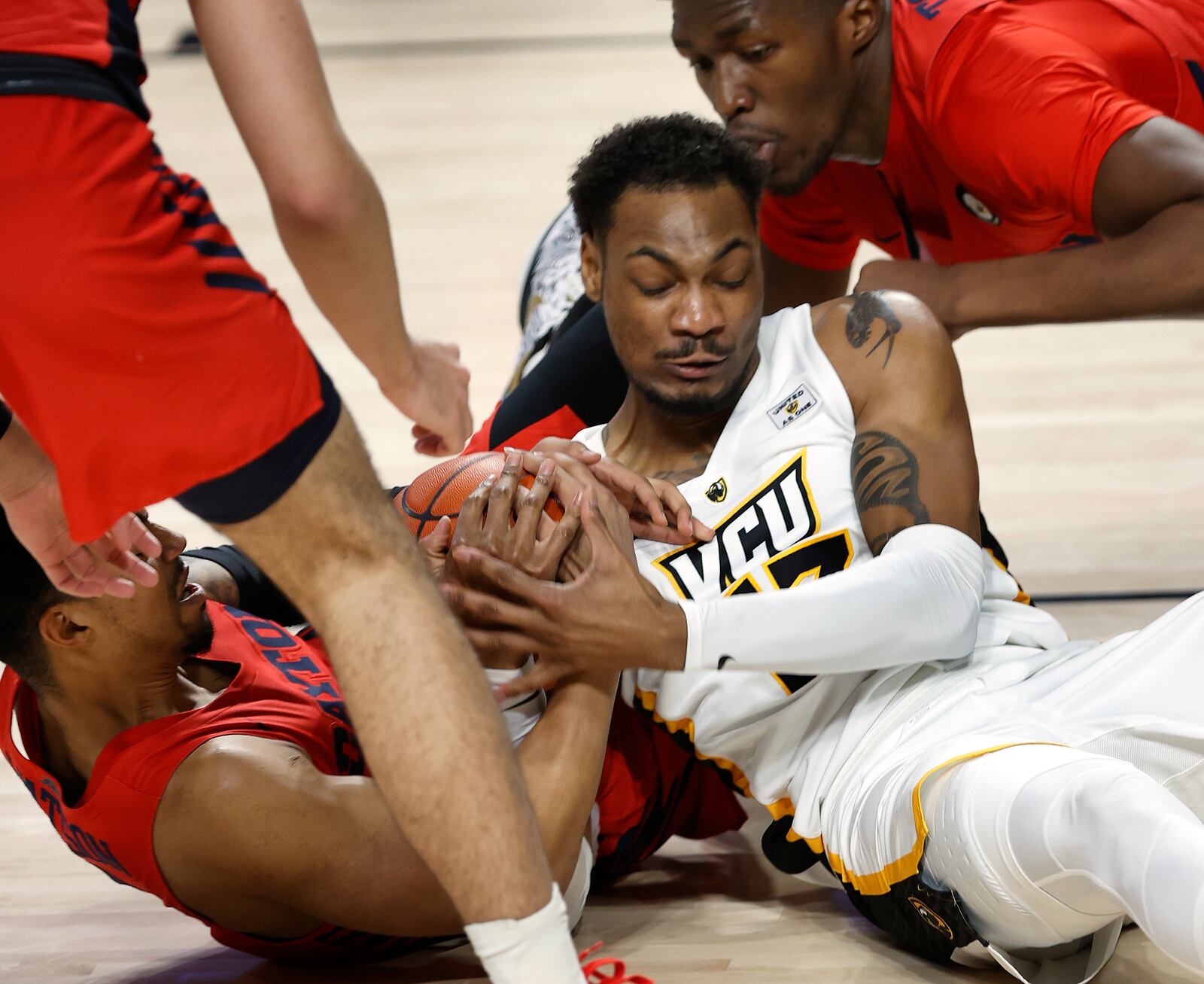 VCU's Corey Douglas Jr. and Dayton's Ibi Watson, left, and Jordy Tshimanga vie for a loose ball in the Siegel Center in Richmond, Va., Sat., Jan. 23, 2021.