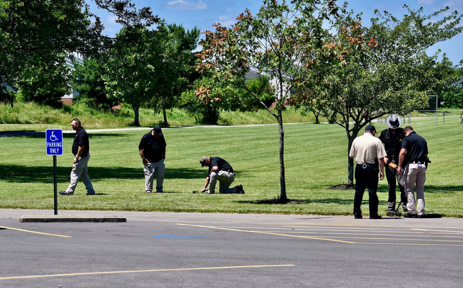 Butler County Sheriff’s detectives search Liberty Park of shell casings on Thursday afternoon. One man was killed and two others injured during shooting at the park Wednesday night. NICK GRAHAM/STAFF