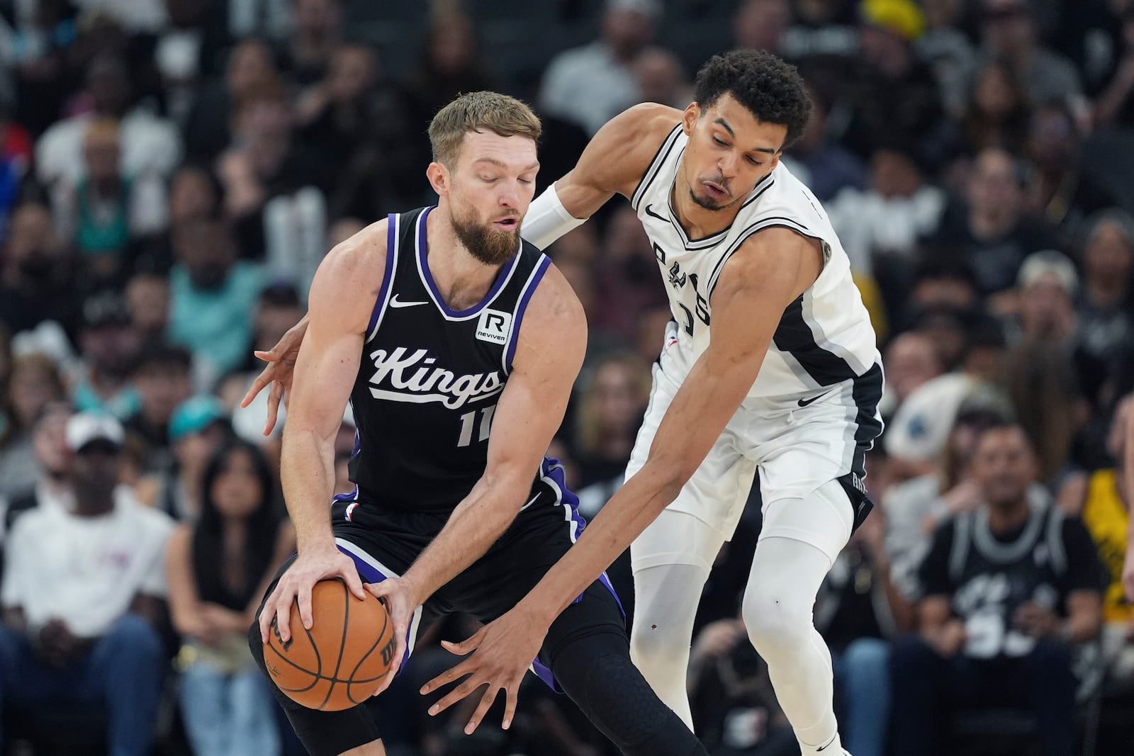 Sacramento Kings forward Domantas Sabonis (11) and San Antonio Spurs center Victor Wembanyama, right, chase the ball during the second half of an NBA basketball game in San Antonio, Monday, Nov. 11, 2024. (AP Photo/Eric Gay)