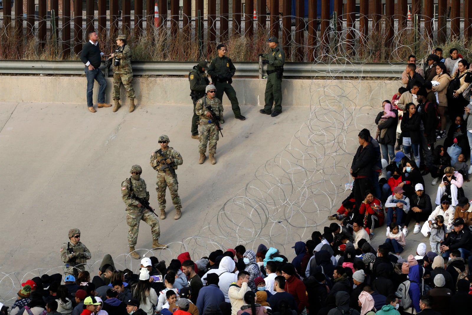 FILE - Migrants congregate on the banks of the Rio Grande at the U.S. border with Mexico on Dec. 20, 2022, where members of the Texas National Guard cordoned off a gap in the U.S. border wall. (AP Photo/Morgan Lee)