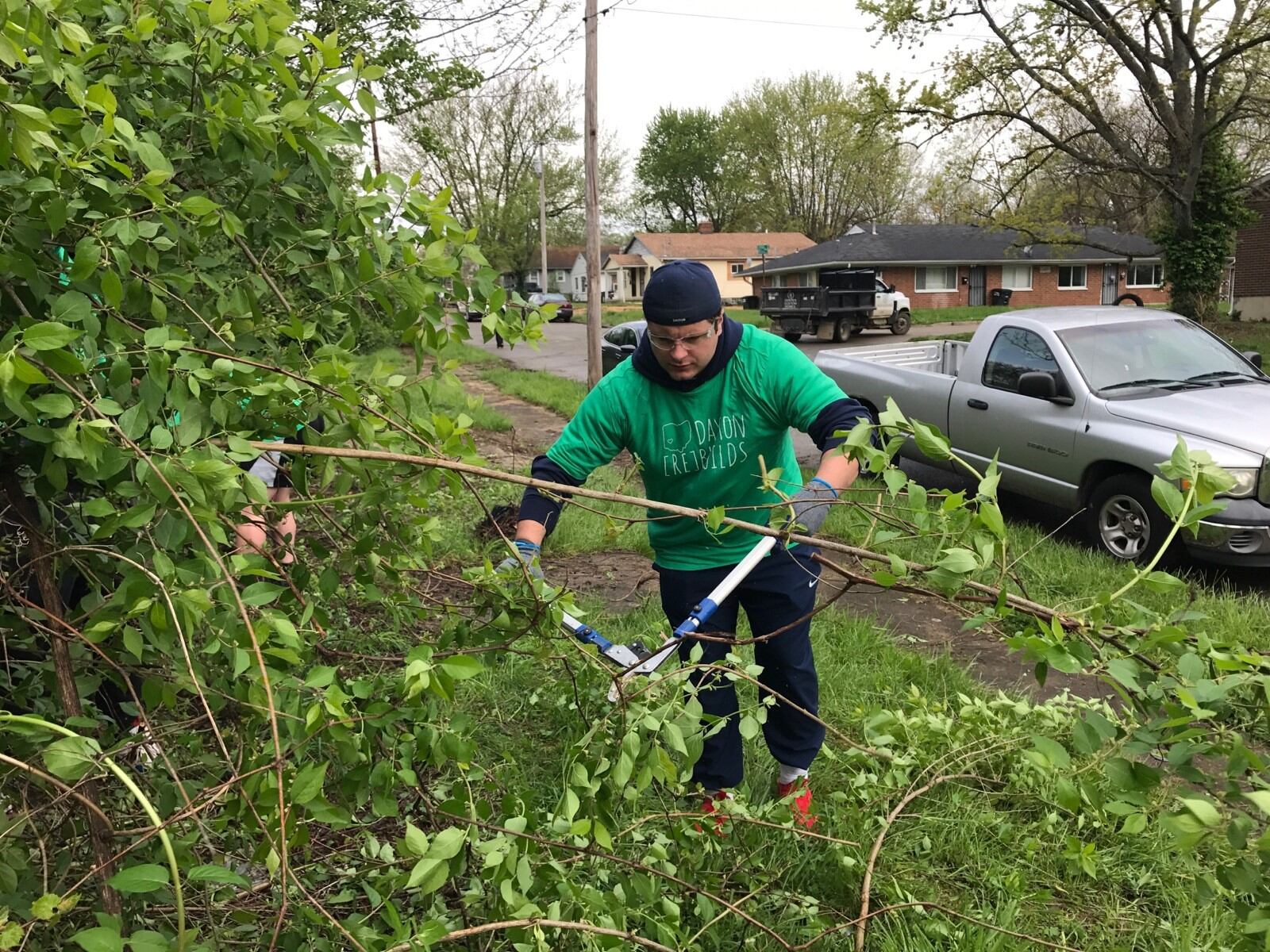 Dayton Flyers offensive lineman George Fanelli works at clearing away some of the overgrowth in front of an abandon house on Weaver Street Saturday as part of the Rebuild Together Dayton effort. (Tom Archdeacon photo)