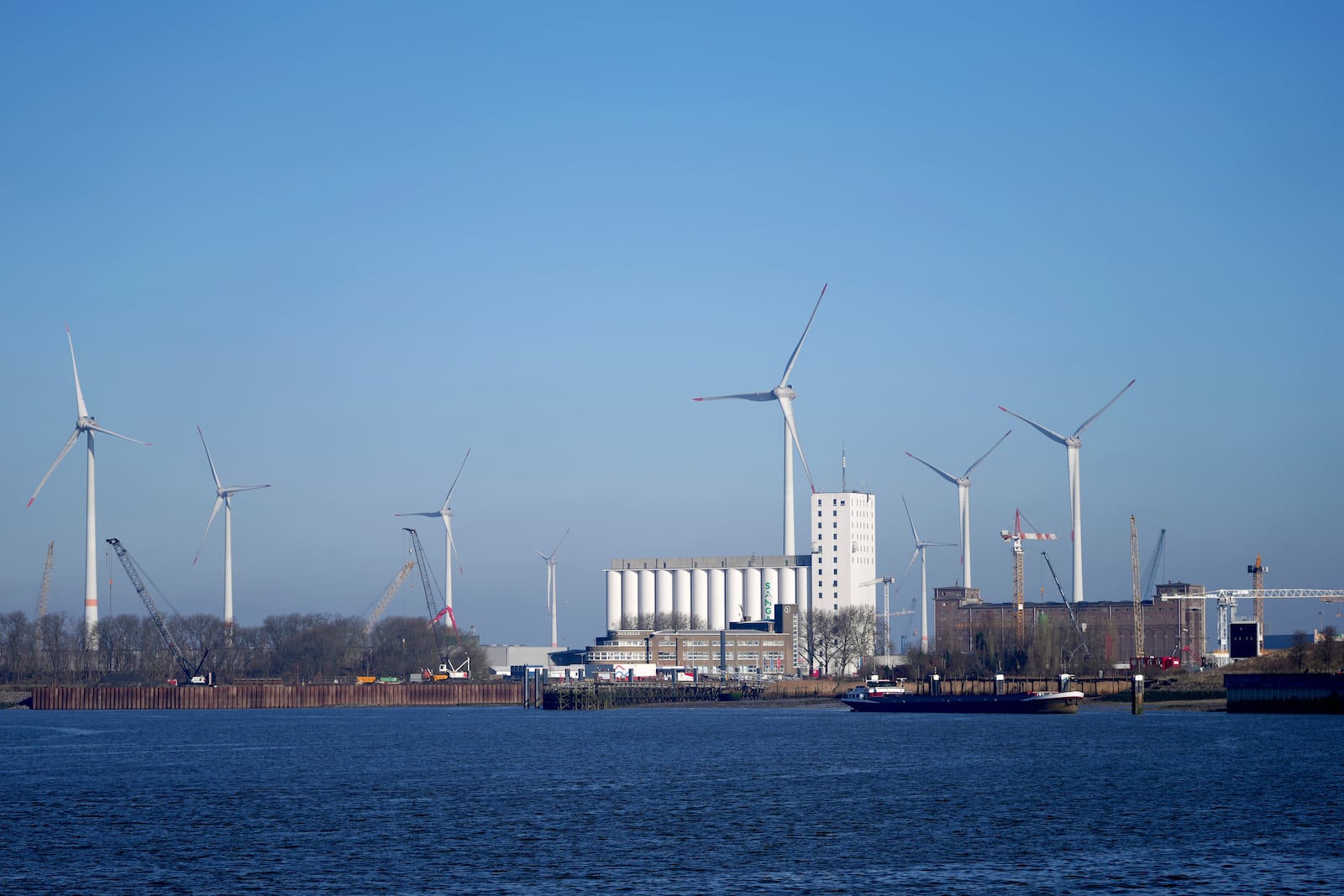 Wind turbines in front of industrial businesses along the River Scheldt in Antwerp, Belgium, Wednesday, Feb. 26, 2025. (AP Photo/Virginia Mayo)