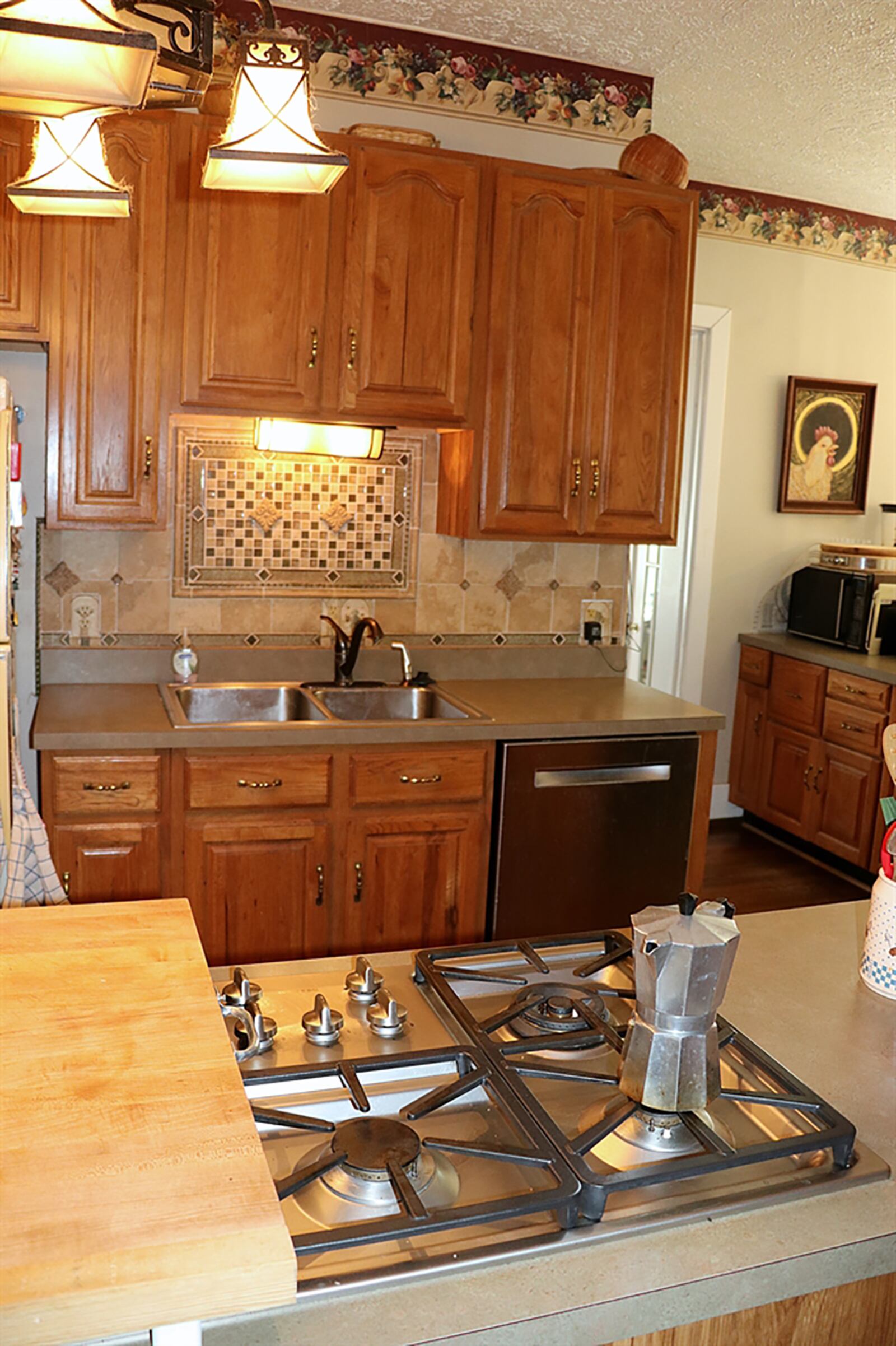 The galley-style kitchen has a long peninsula counter with built-in gas cooktop and grill. Cabinetry surrounds a sink and appliances along the opposite wall. CONTRIBUTED PHOTO BY KATHY TYLER