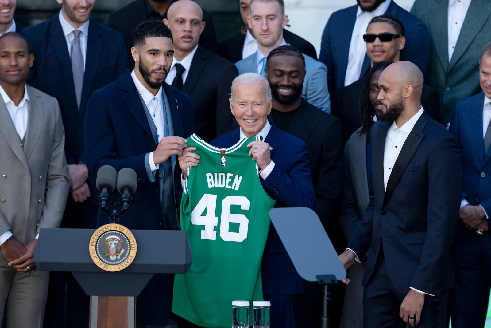 President Joe Biden, center, flanked by Boston Celtics players Jayson Tatum, left, and Derrick White, right, holds a jersey presented by the team at an event to celebrate their victory in the 2024 National Basketball Association Championship, on the South Lawn of the White House in Washington, Thursday, Nov. 21, 2024. (AP Photo/Ben Curtis)