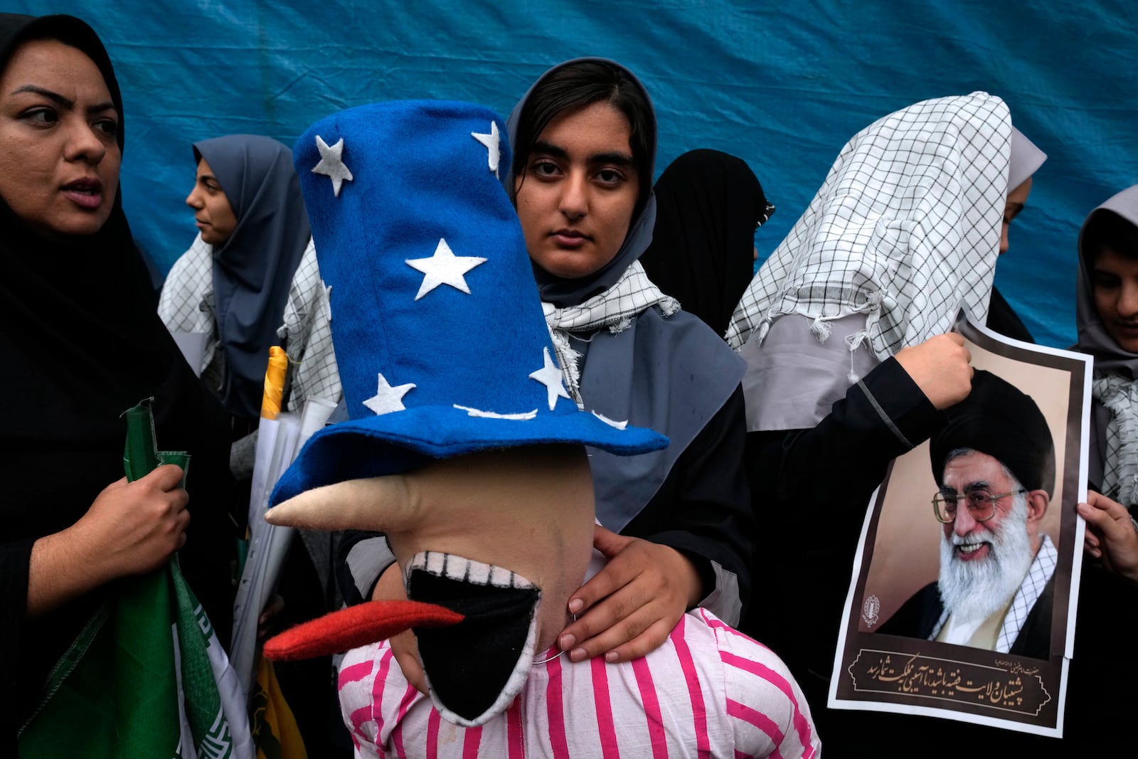 A schoolgirl holds an effigy of the Uncle Sam as another one holds a poster of the Iranian Supreme Leader, Ayatollah Ali Khamenei, in an annual rally in front of the former U.S. Embassy in Tehran, Iran, Sunday, Nov. 3, 2024, marking the 45th anniversary of Iranian students' takeover of the embassy, starting a hostage crisis. (AP Photo/Vahid Salemi)