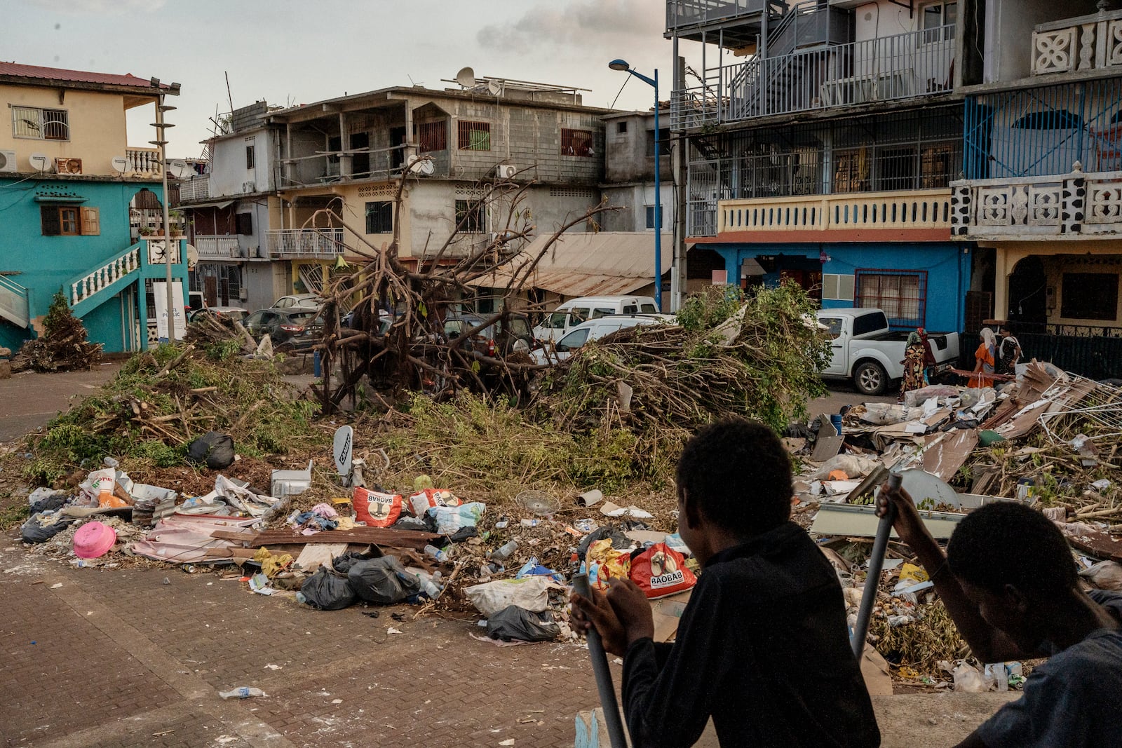 Kids play on a public square filled with garbage and debris, Thursday, Dec. 19, 2024, in Mamoudzou, Mayotte. (AP Photo/Adrienne Surprenant)