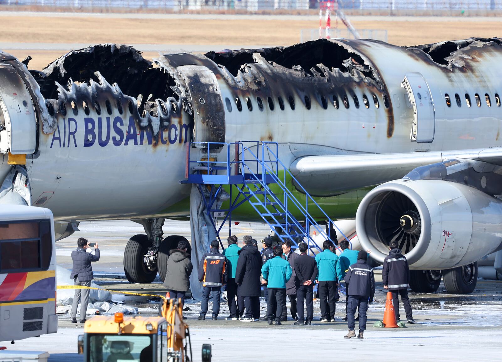 Firefighters and other officials visit the site where an Air Busan airplane caught fire at Gimhae International Airport in Busan, South Korea, Wednesday, Jan. 29, 2025. (Son Hyung-joo/Yonhap via AP)