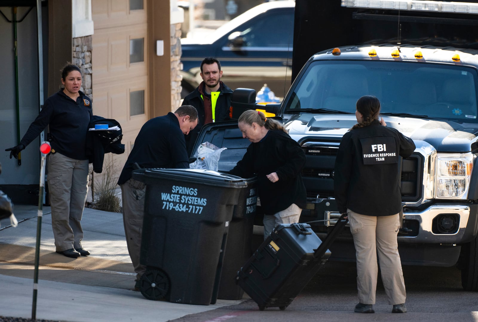 Investigators search the garbage outside of a townhouse in northeastern Colorado Springs, Colo., Thursday, Jan. 2, 2025, as the investigation connected to the explosion of a Tesla Cybertruck outside President-elect Donald Trump's Las Vegas hotel continues. (Parker Seibold /The Gazette via AP)