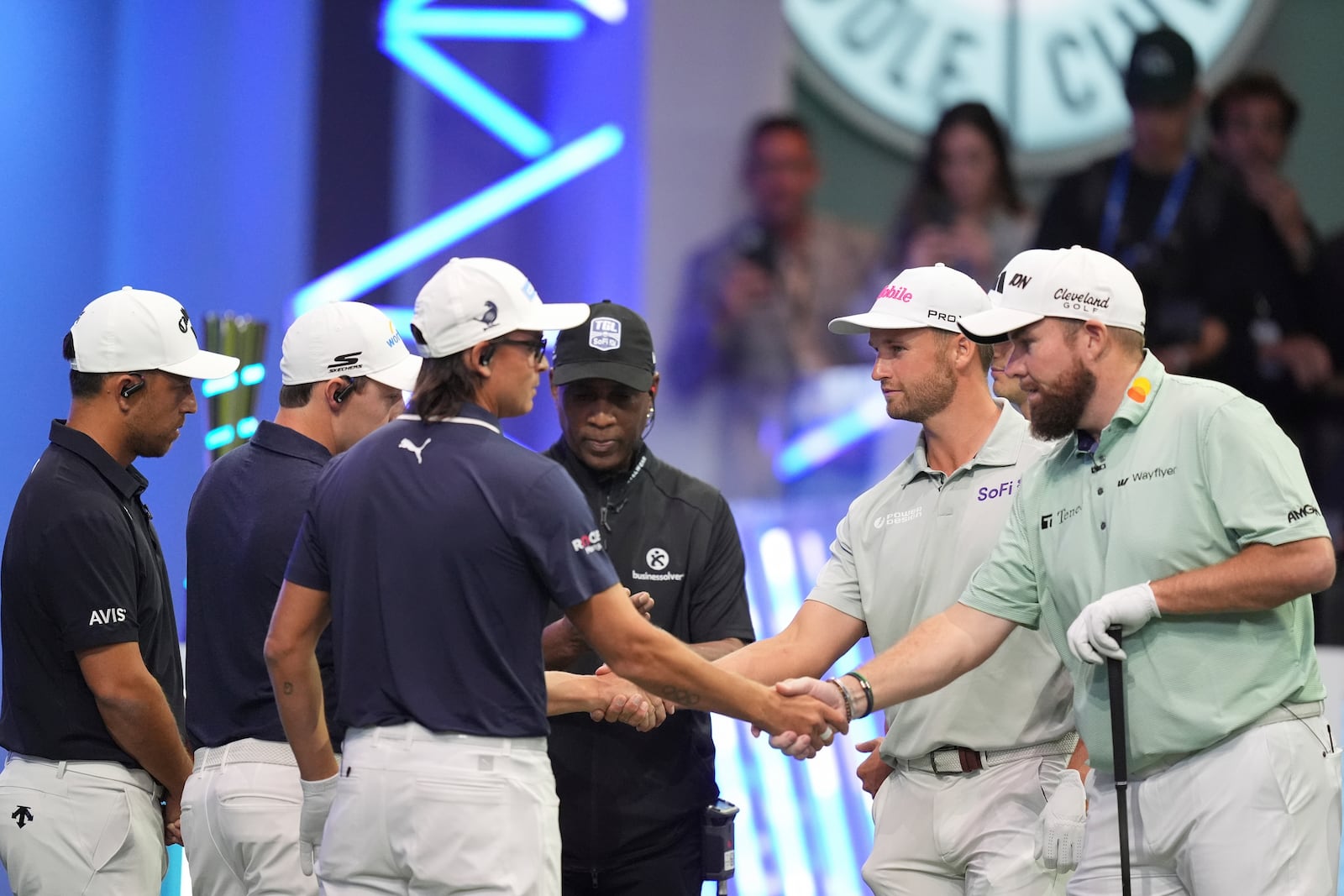 Rickie Fowler of New York Golf Club, third left, shakes hands with Shane Lowry of The Bay Golf Club as the teams prepare for the start of the inaugural match of the TMRW Golf League, Tuesday, Jan. 7, 2025, in Palm Beach Gardens, Fla. TGL features six teams of four players competing against each other in a tech-infused arena the size of a football field. (AP Photo/Rebecca Blackwell)