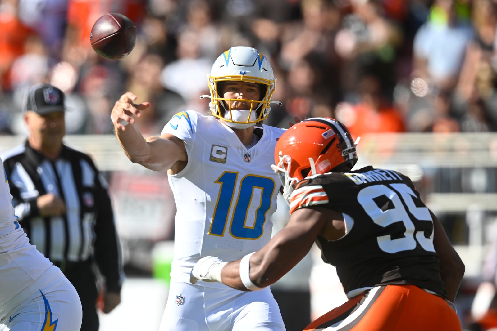 Los Angeles Chargers quarterback Justin Herbert (10) passes over Cleveland Browns defensive end Myles Garrett (95) in the first half of an NFL football game Sunday, Nov. 3, 2024, in Cleveland. (AP Photo/David Richard)