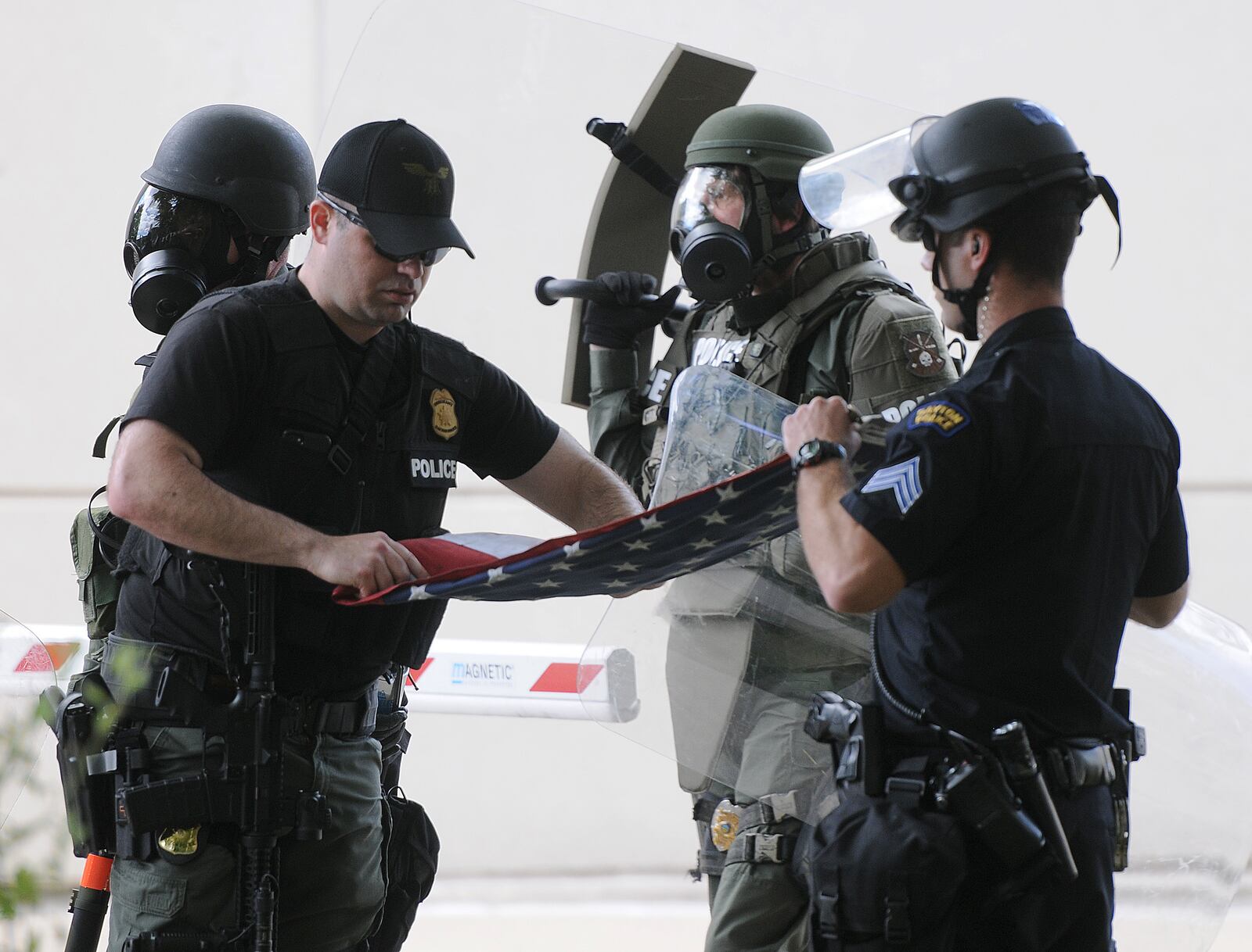 Members of the Dayton Police Department fold the American flag they recovered from protesters Saturday, May 30, 2020. Protesters cut it down and took from the Safety Building. MARSHALL GORBY / STAFF