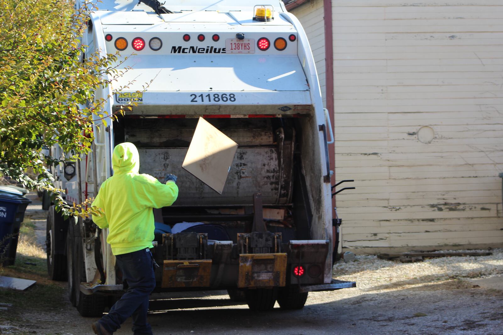 A waste collection worker throws trash into the back of trash truck. CORNELIUS FROLIK / STAFF