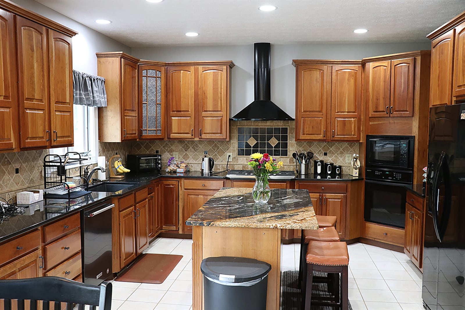 The kitchen has been updated with cherry cabinetry, granite countertops and Travertine backsplash. An island has a thick-cut granite countertop, and the cherry cabinetry creates a U-shaped workspace that surrounds stainless-steel appliances that include a gas cooktop and double wall ovens. CONTRIBUTED PHOTO BY KATHY TYLER