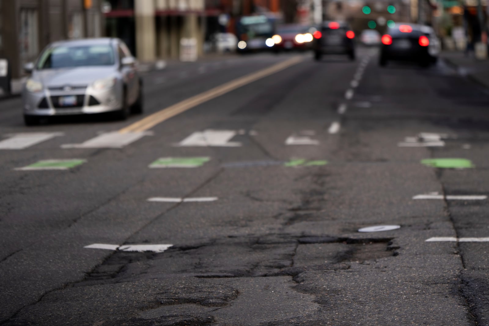 Cars drive along W Burnside Street as cracks are seen in the road on Thursday, Feb. 6, 2025, in Portland, Ore. (AP Photo/Jenny Kane)