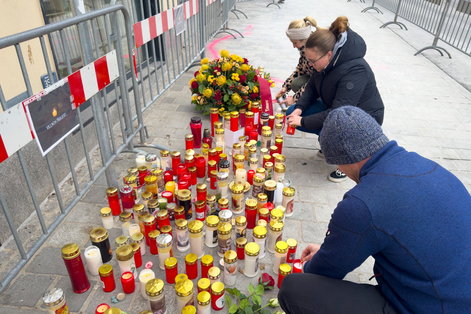 People light candles at the site of stabbing a day after an attack that left a 14-year-old dead and five others injured, in Villach, Austria, Sunday, Feb. 16, 2025. (AP Photo/Darko Bandic)