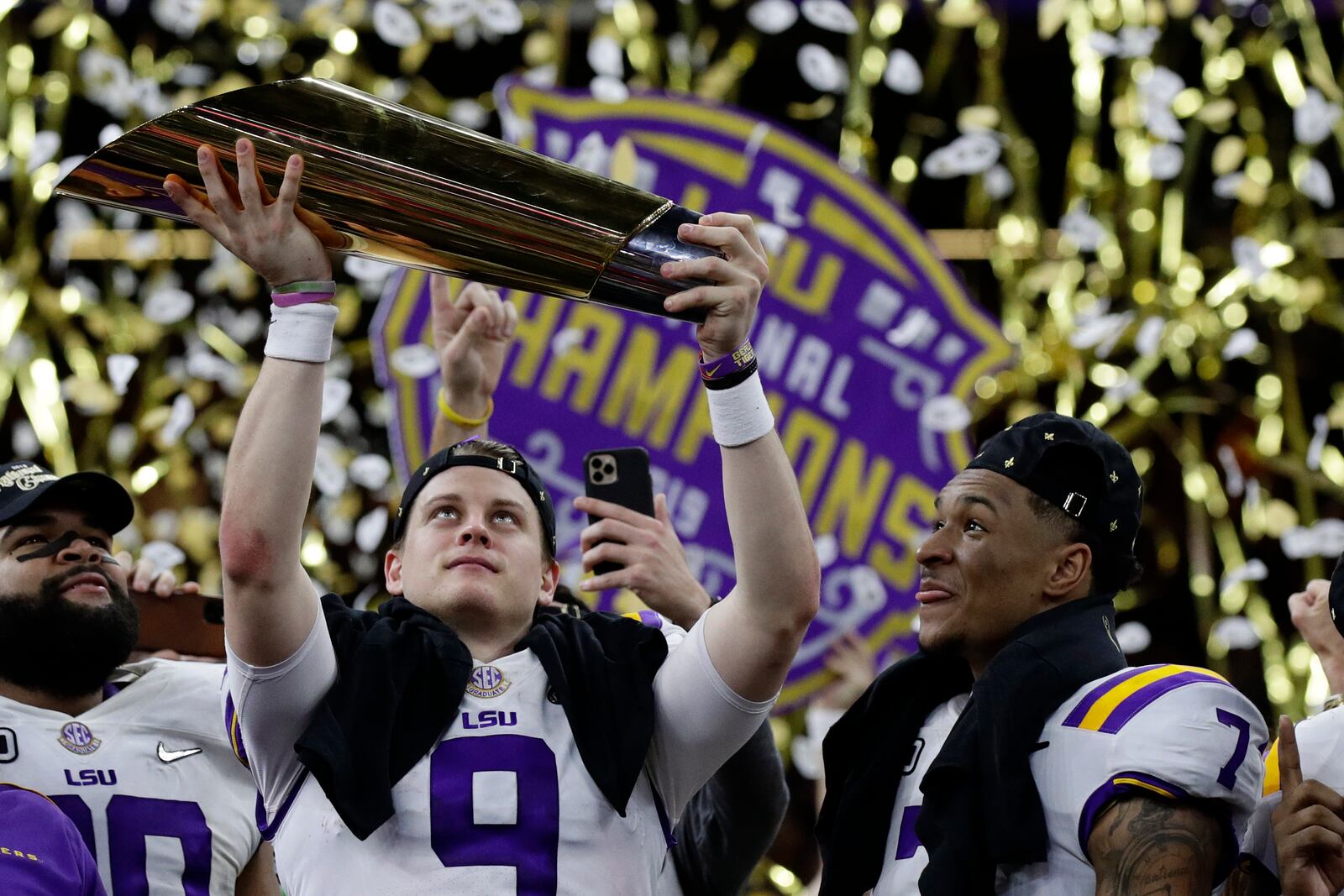 FILE - LSU quarterback Joe Burrow holds the trophy as safety Grant Delpit looks on after a NCAA College Football Playoff national championship game against Clemson, in New Orleans, Jan. 13, 2020. (AP Photo/Sue Ogrocki, File)