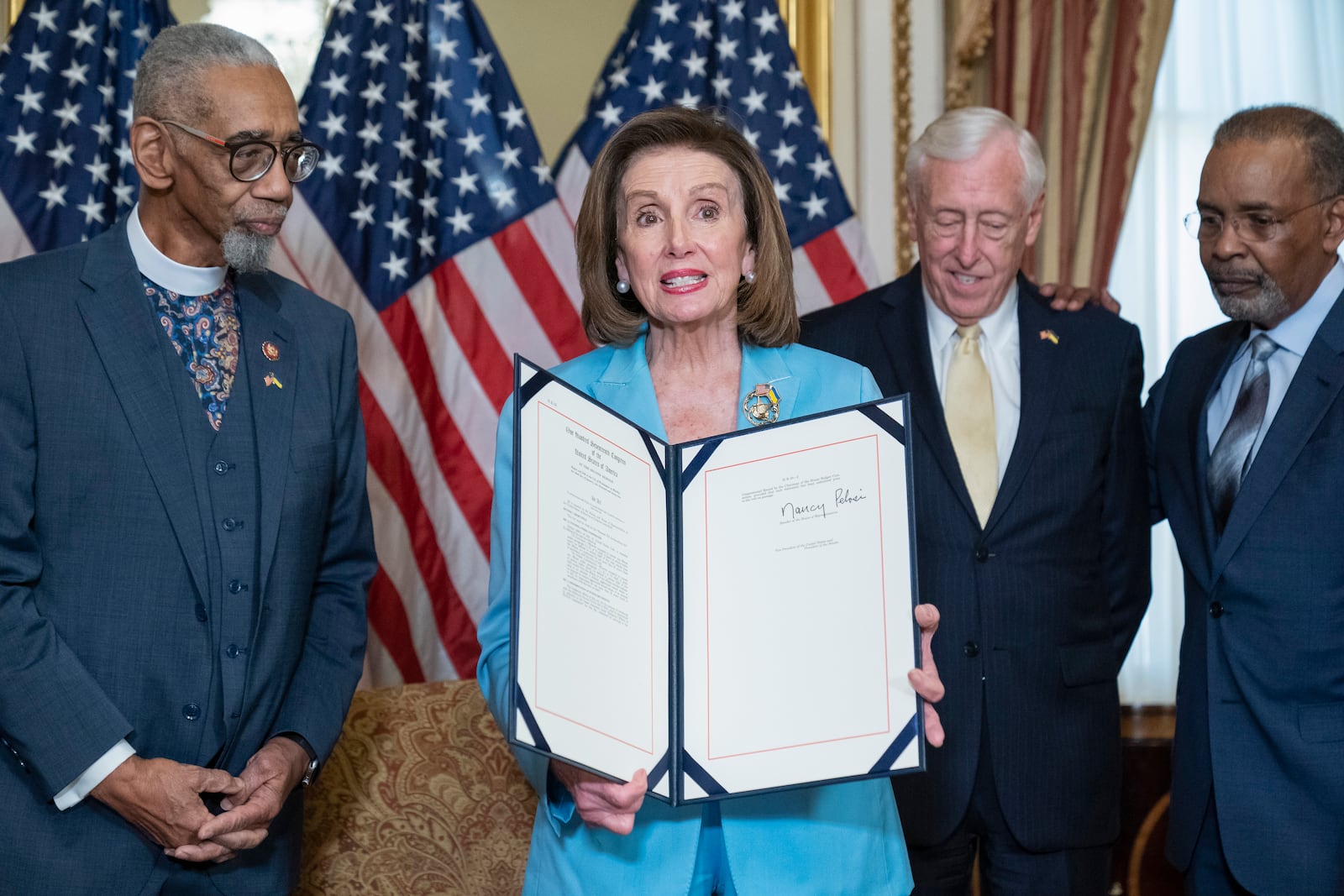 House Speaker Nancy Pelosi of Calif., holds up H.R. 55, the "Emmett Till Antilynching Act" which designates lynching as a hate crime under federal law, during a signing ceremony on Capitol Hill in Washington, Wednesday, March 16, 2022. Joining Pelosi are Rep. Bobby Rush, D-Ill., left, Pelosi, House Majority Leader Steny Hoyer of Md., and radio host Joe Madison. (AP Photo/Alex Brandon)