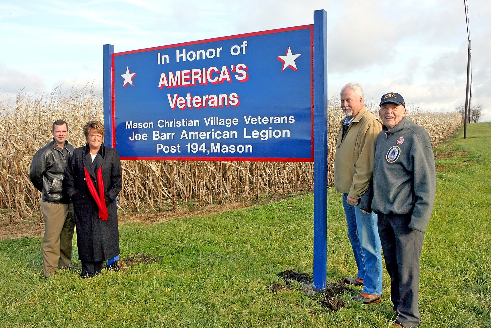 Warren County Commissioners Dave Young and Pat South along with Mason Mayor Don Prince and Mason Christian Village Veterans Association past commander Victor Carman pose with the newly erected sign Nov. 30 honoring Warren County veterans. The sign is located at the Schappacher Farm along Ohio 42 in Mason.