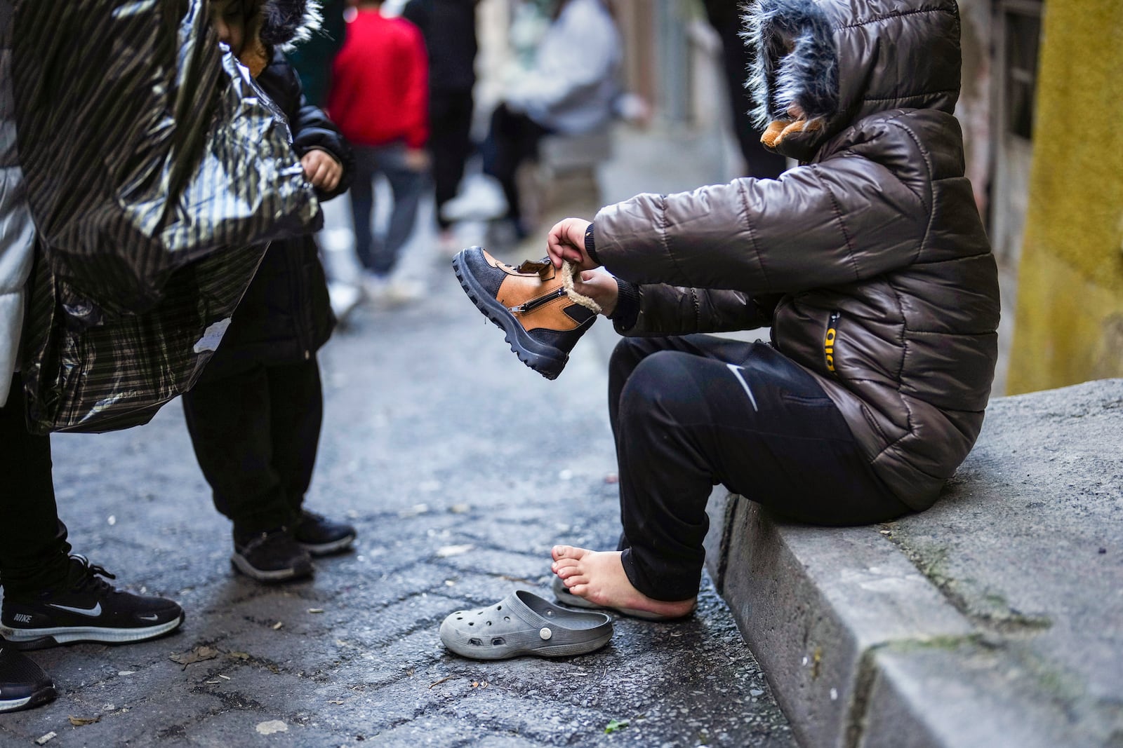 A child tries on a pair of new boots that were handed out by volunteers in the Tarlabasi neighborhood in Istanbul, Turkey, Saturday, Dec. 14, 2024. (AP Photo/Francisco Seco)