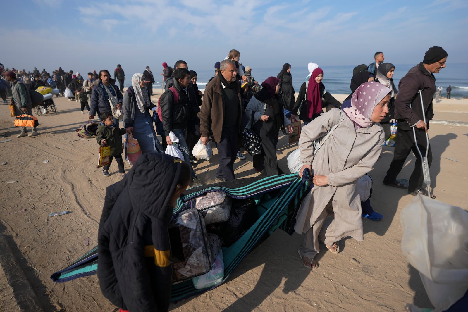 Carrying their belongings displaced Palestinians walk on a road to return to their homes in the northern Gaza Strip, Tuesday, Jan. 28, 2025, after Israel's decision to allow thousands of them to go back for the first time since the early weeks of the 15-month war with Hamas. (AP Photo/Abdel Kareem Hana)