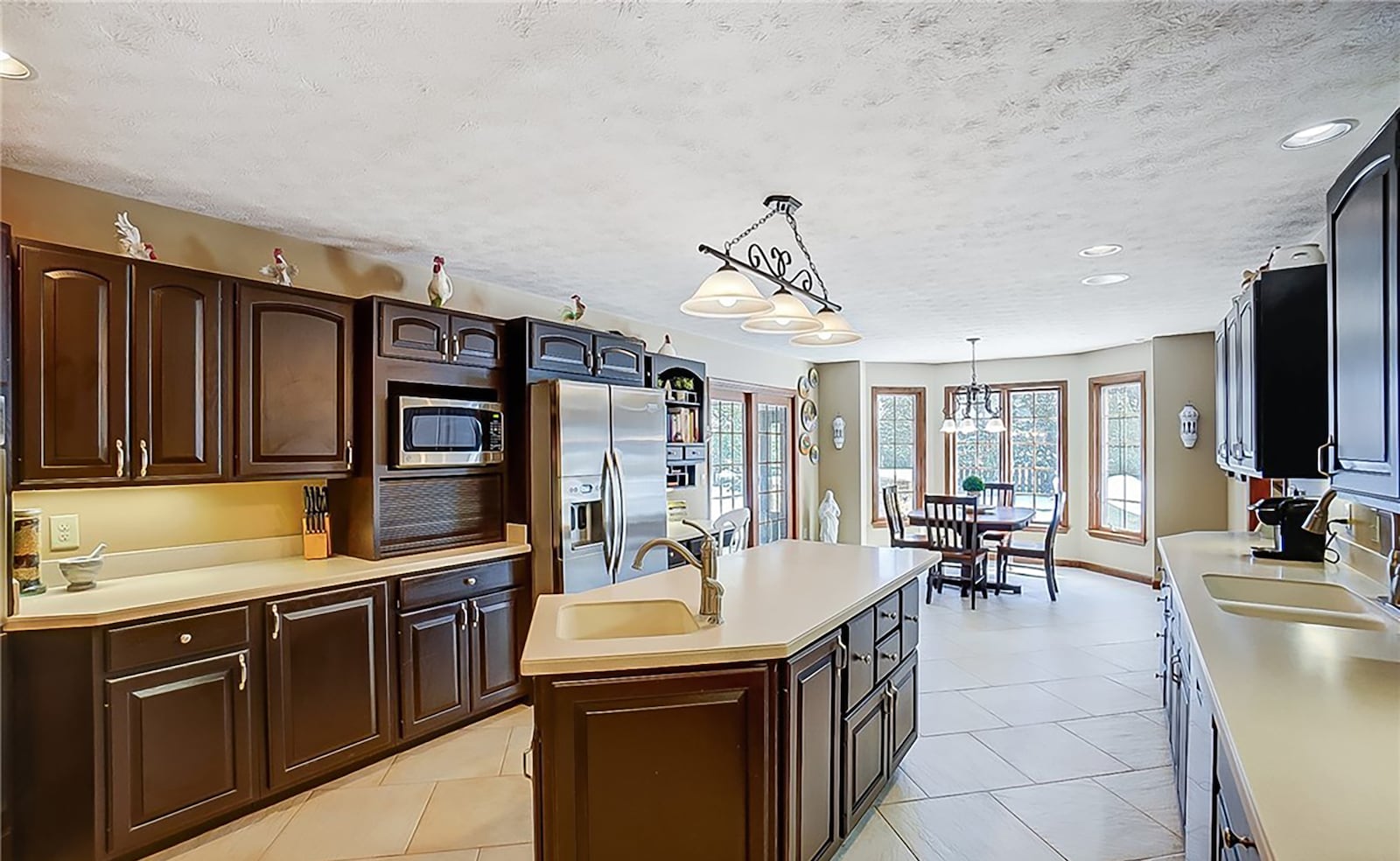 The eat in kitchen has a breakfast area with bay window, an island with additional bar seating area, custom cabinets and high-end stainless appliances.