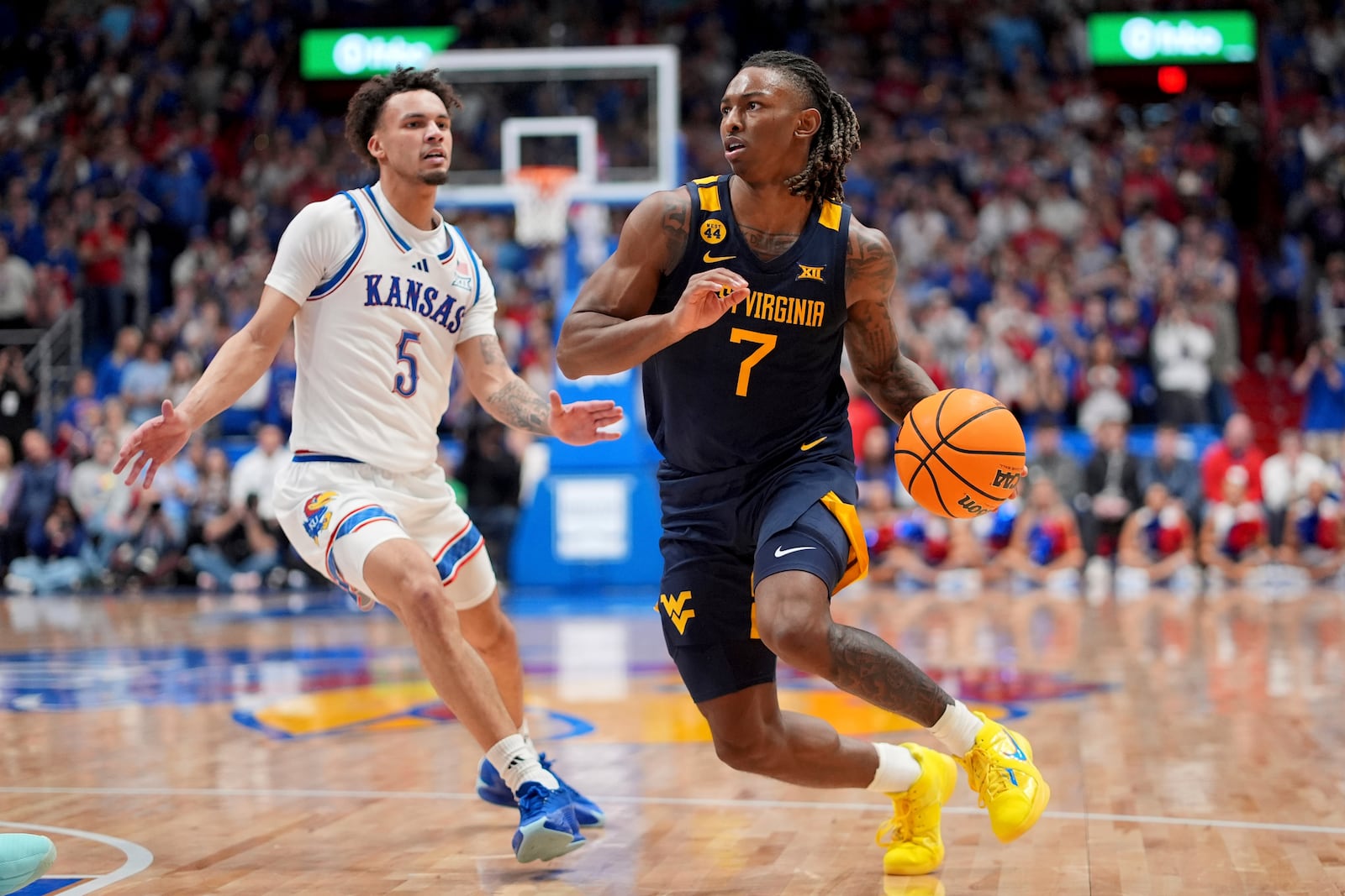 West Virginia guard Javon Small (7) drives past Kansas guard Zeke Mayo (5) during the second half of an NCAA college basketball game, Tuesday, Dec. 31, 2024, in Lawrence, Kan. West Virginia won 62-61(AP Photo/Charlie Riedel)