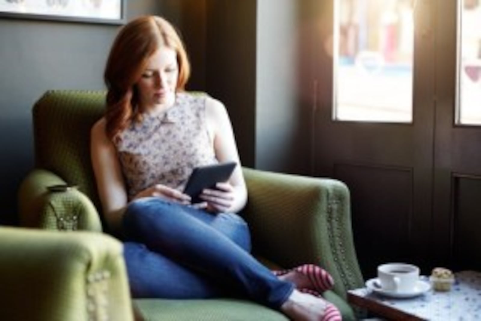 Woman reading ebook on tablet in coffee shop