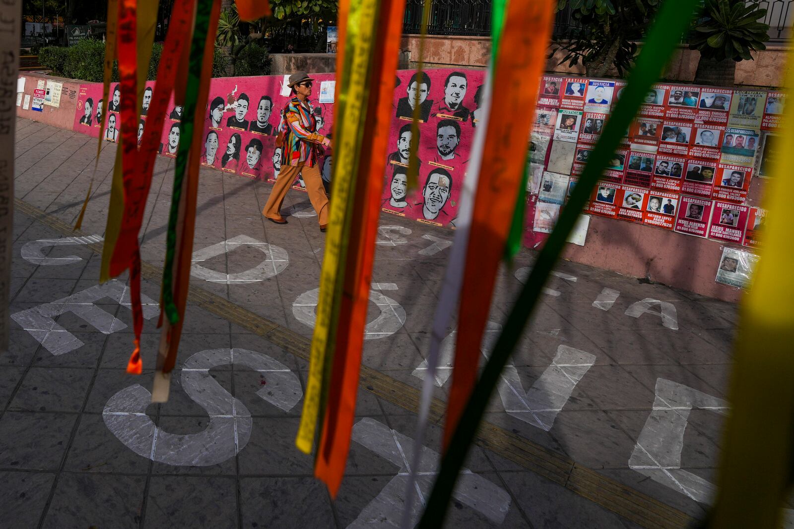 A pedestrian walks over a sign that reads in Spanish, "Where are they?" referencing missing people, at Obregon square in Culiacan, Sinaloa state, Mexico, Thursday, Feb. 27, 2025. (AP Photo/Fernando Llano)