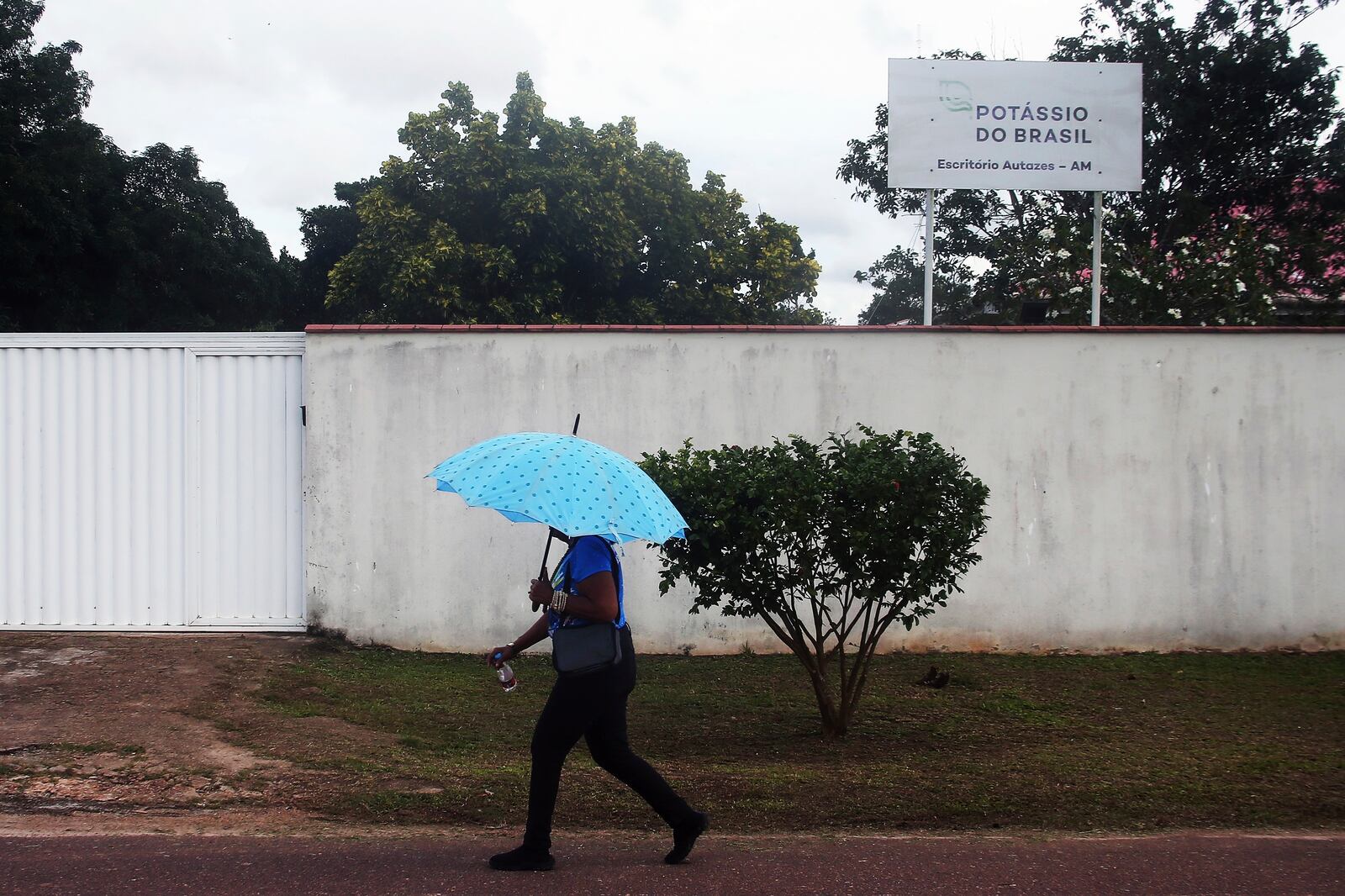 A woman walks near a sign for the Brazil Potash Corp. in Autazes, Amazonas state, Brazil, Wednesday, Feb. 19, 2025. (AP Photo/Edmar Barros)