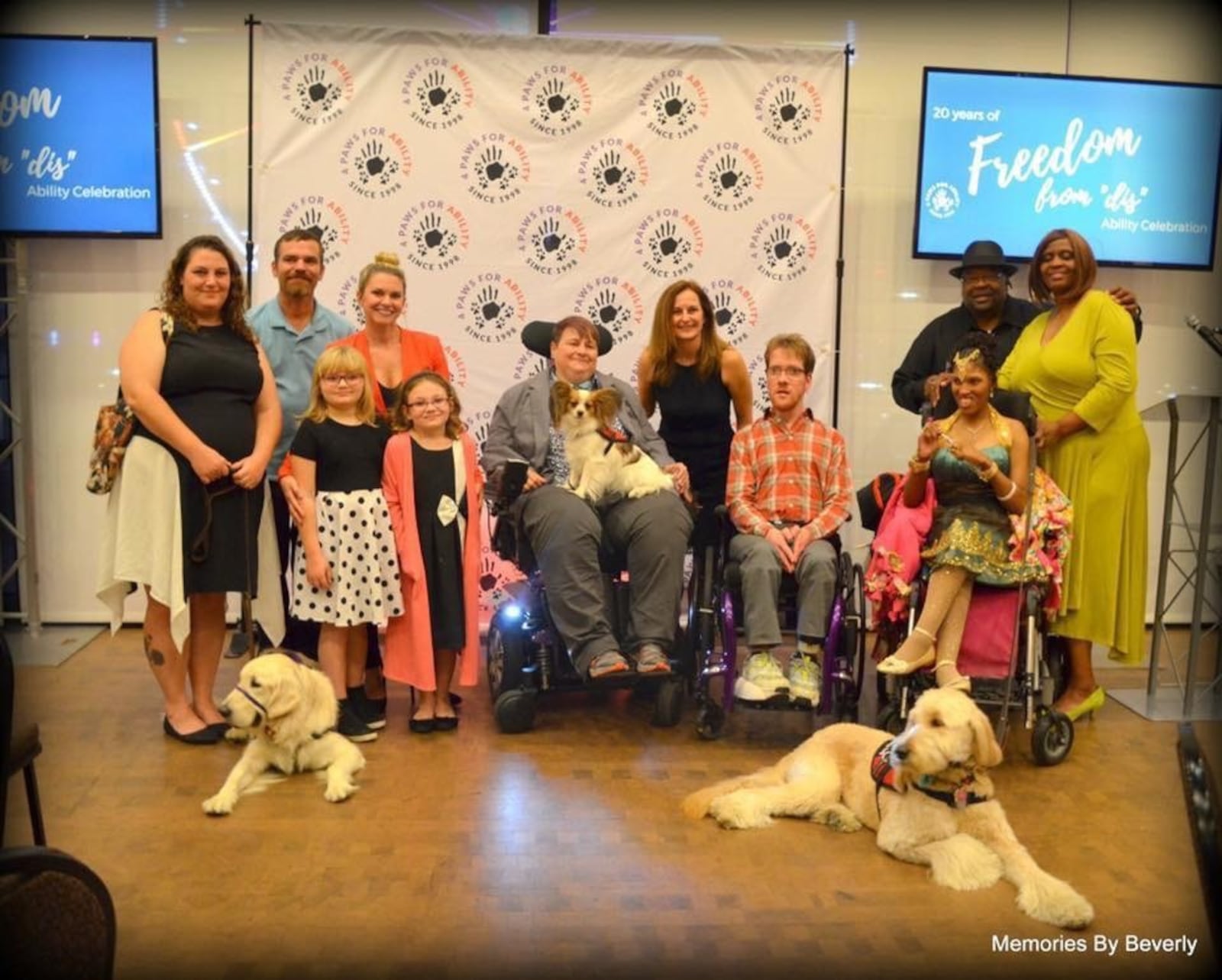 Shirk is surrounded by the 4 Paws “family” on the organization’s 20th anniversary celebration. On her lap is Aiko, Shirk’s third service dog. 