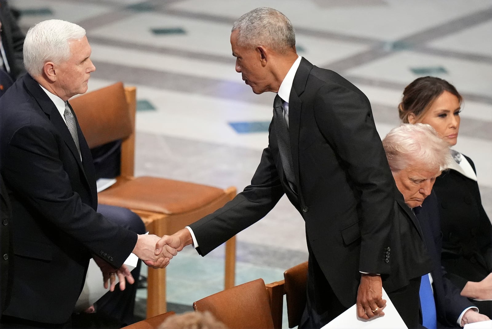 Former President Barack Obama shakes hands with former Vice President Mike Pence before the state funeral for former President Jimmy Carter at Washington National Cathedral in Washington, Thursday, Jan. 9, 2025, as President-elect Donald Trump sits with Melania Trump at right. (AP Photo/Jacquelyn Martin)