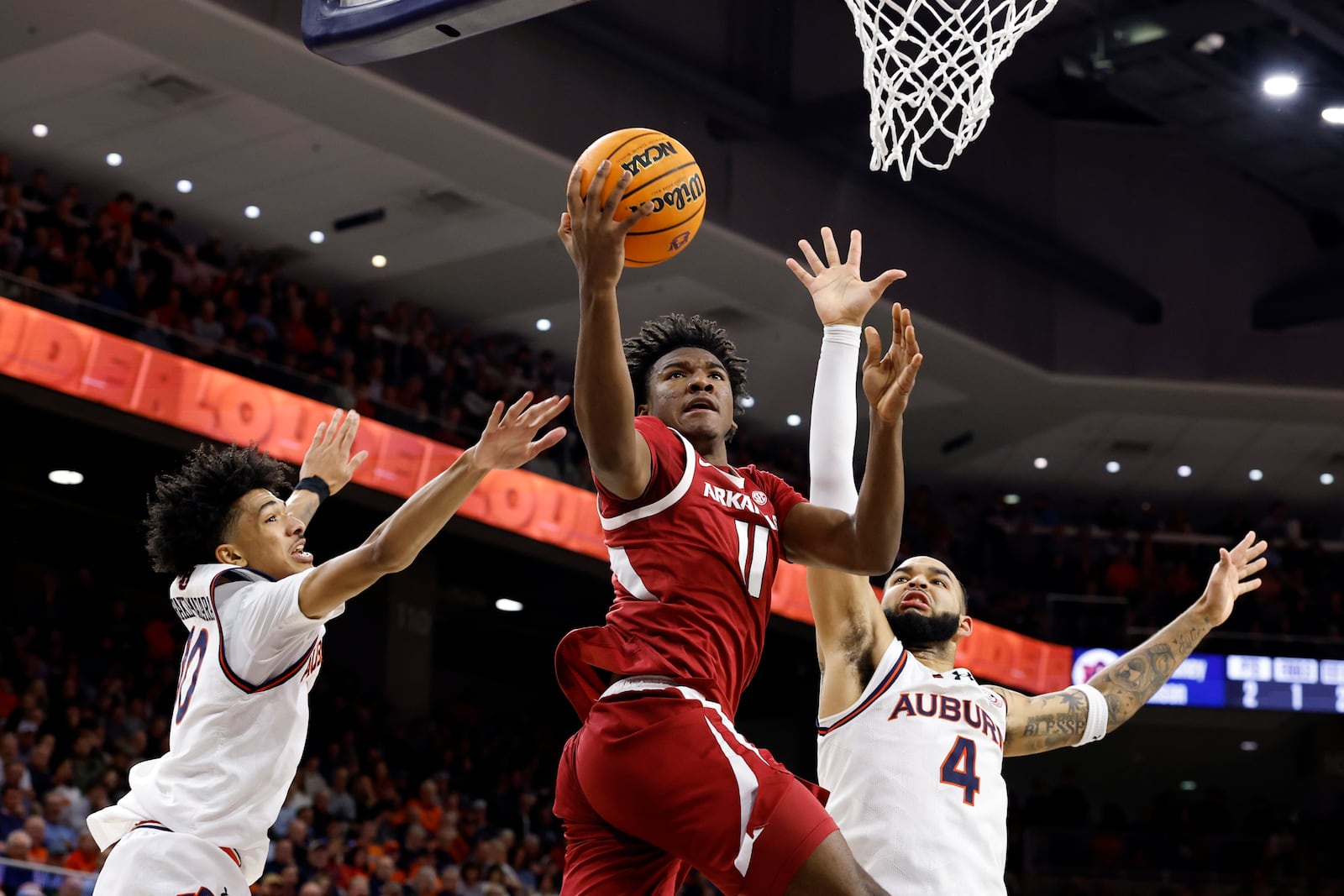 Arkansas forward Karter Knox (11) goes to the basket between Auburn guard Chad Baker-Mazara (10) and forward Johni Broome (4) during the first half of an NCAA college basketball game, Wednesday, Feb. 19, 2025, in Auburn, Ala. (AP Photo/Butch Dill)