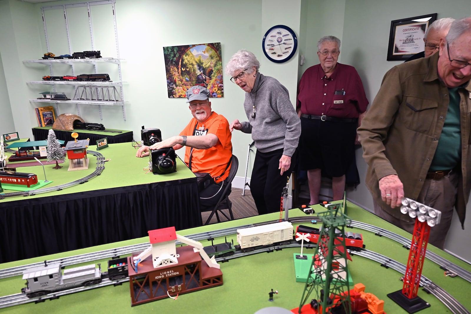 Erhardt (seated in orange) operates his trains for visitors at Bethany, Barbara Evans, David Linegang and Vic Bean.