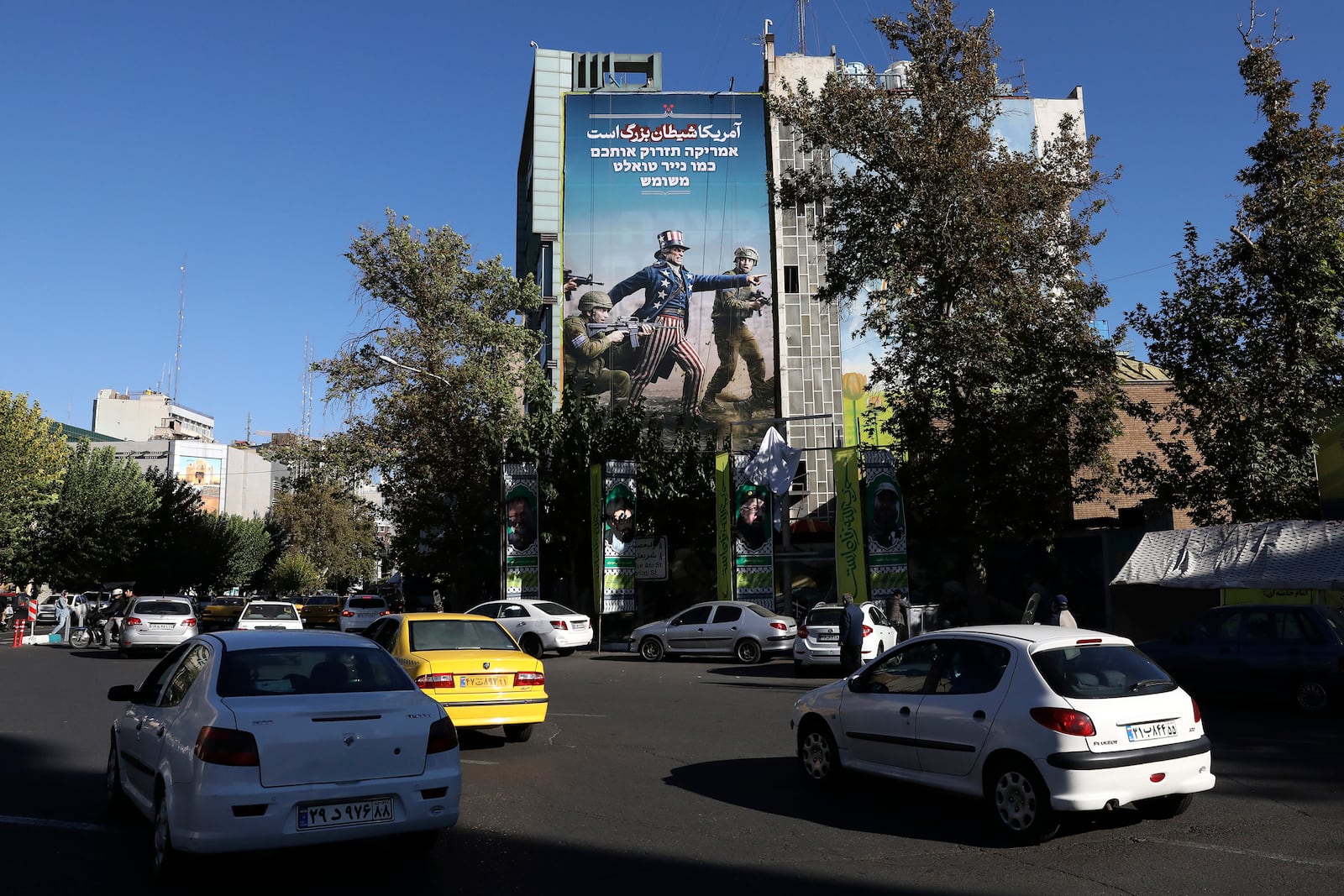 Vehicles drive past an anti-U.S. and anti-Israel banner with writing in Farsi reading: "America is the great Satan", and in Hebrew "America will throw you away like used toilet paper", at the Felestin (Palestine) Sq. in downtown Tehran, Iran, Wednesday, Nov. 6, 2024. (AP Photo/Vahid Salemi)