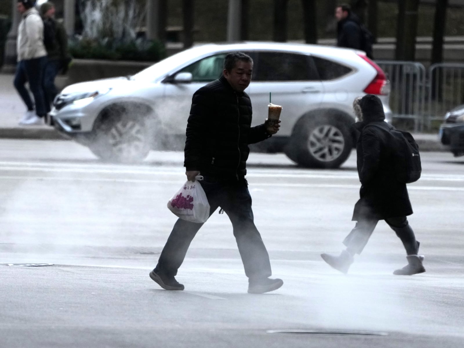 Pedestrians walk through steam rising out of manhole covers as an Arctic blast brings single-digit temperatures with wind chills below zero on Thursday, Dec. 12, 2024, in Chicago. (AP Photo/Charles Rex Arbogast)