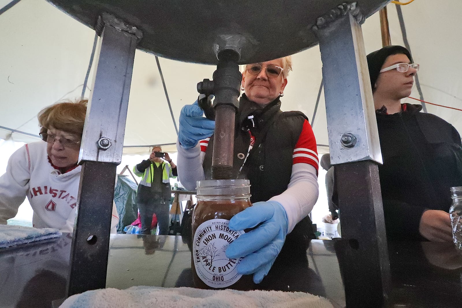 Volunteers fill jars of hot apple butter Saturday, Oct. 8, 2022 at the Enon Apple Butter Festival. BILL LACKEY/STAFF