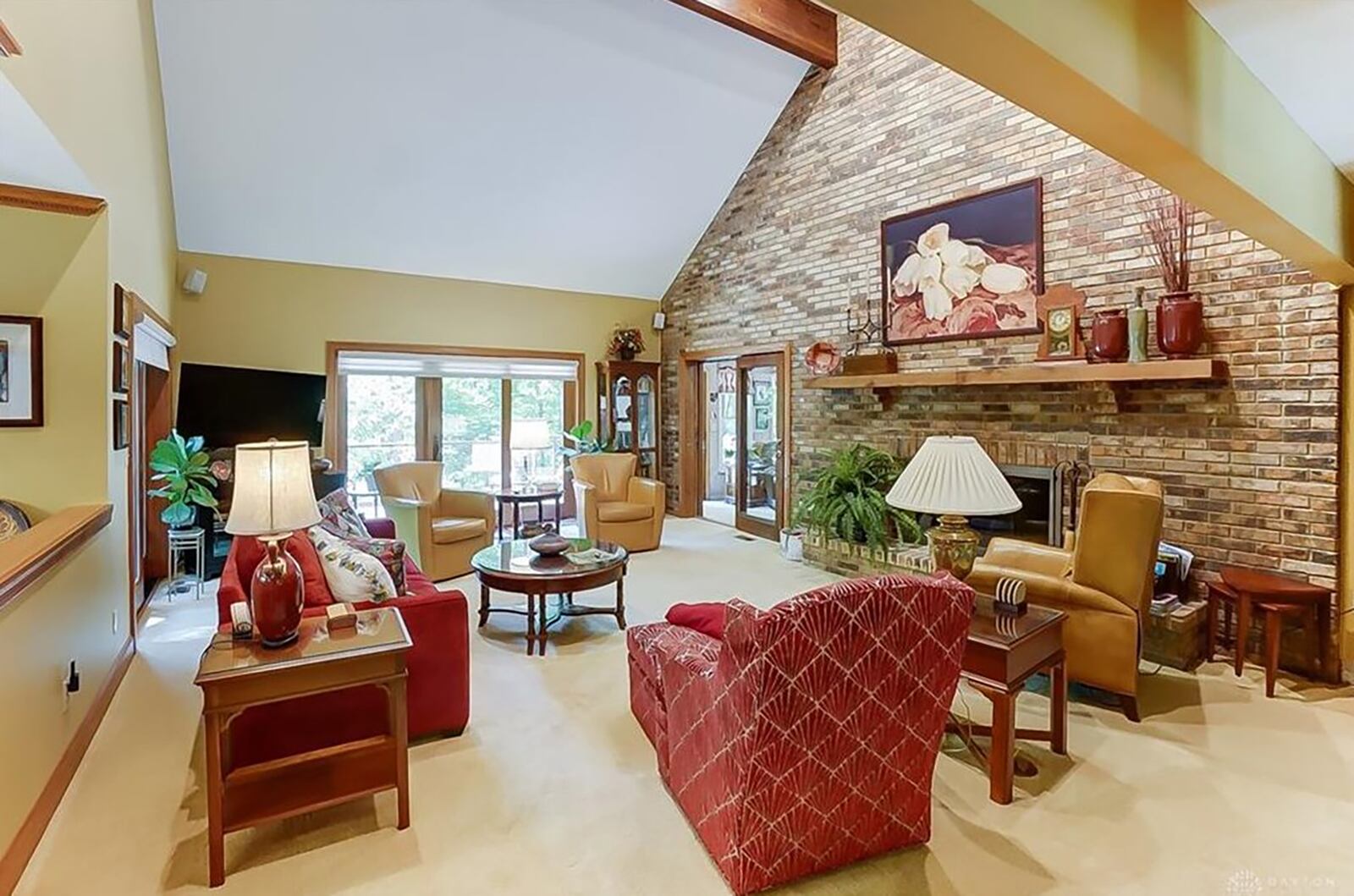 The great room has a vaulted ceiling and brick accent wall with woodburning fireplace with glass doors and gas starter. It steps out to the upper level deck.