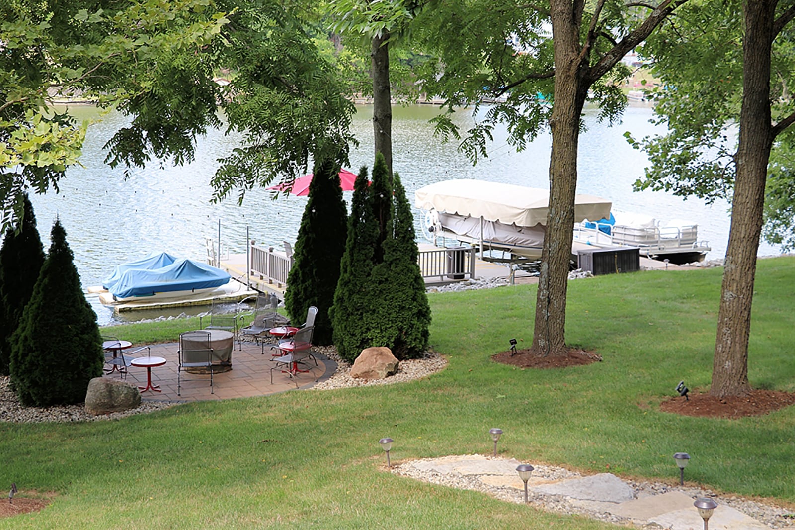 Limestone steps extend past the wooden desk stairs down to the lower yard and docks. Evergreens create a natural privacy fence around the fire pit and paver-brick patio. Two docks allow for watercraft parking for jet skis and small boats. CONTRIBUTED PHOTO BY KATHY TYLER