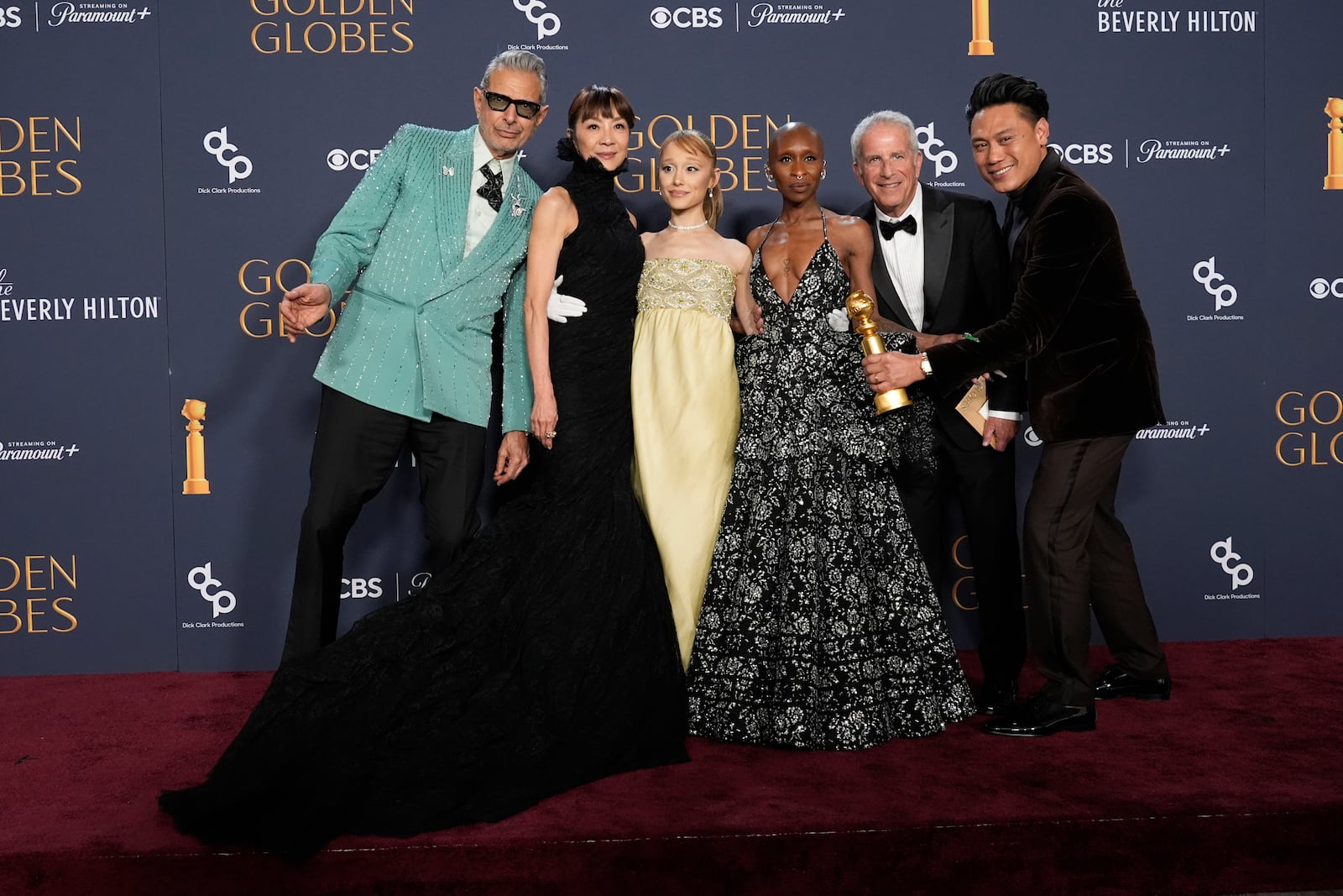 Jeff Goldblum, from left, Michelle Yeoh, Ariana Grande, Cynthia Erivo, Marc Platt, and Jon M. Chu pose with the award for cinematic and box office achievement for "Wicked" in the press room during the 82nd Golden Globes on Sunday, Jan. 5, 2025, at the Beverly Hilton in Beverly Hills, Calif. (AP Photo/Chris Pizzello)