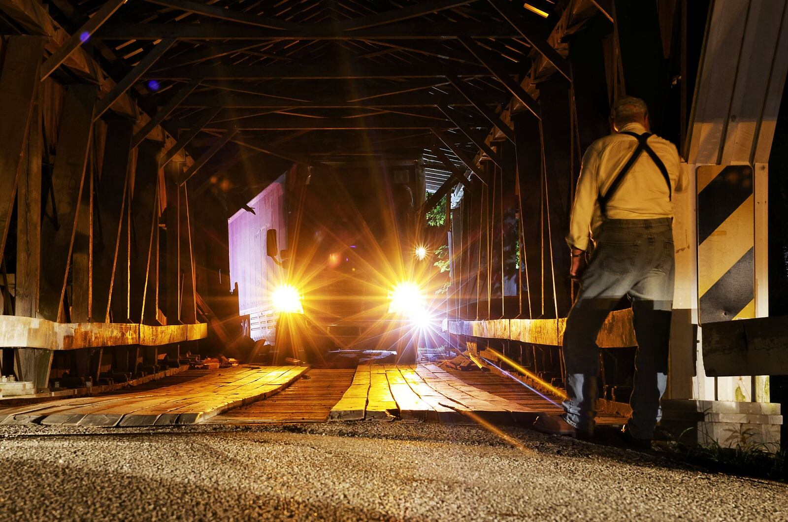 Doug Brubaker, who lives nearby, looks at the damage after a semi tractor trailer got stuck attempting to cross the covered, one lane Brubaker Bridge on Brubaker Road Friday evening, Aug. 5, 2022 in Preble County. The roof of the bridge suffered damage when the trailer became lodged under it. NICK GRAHAM/STAFF