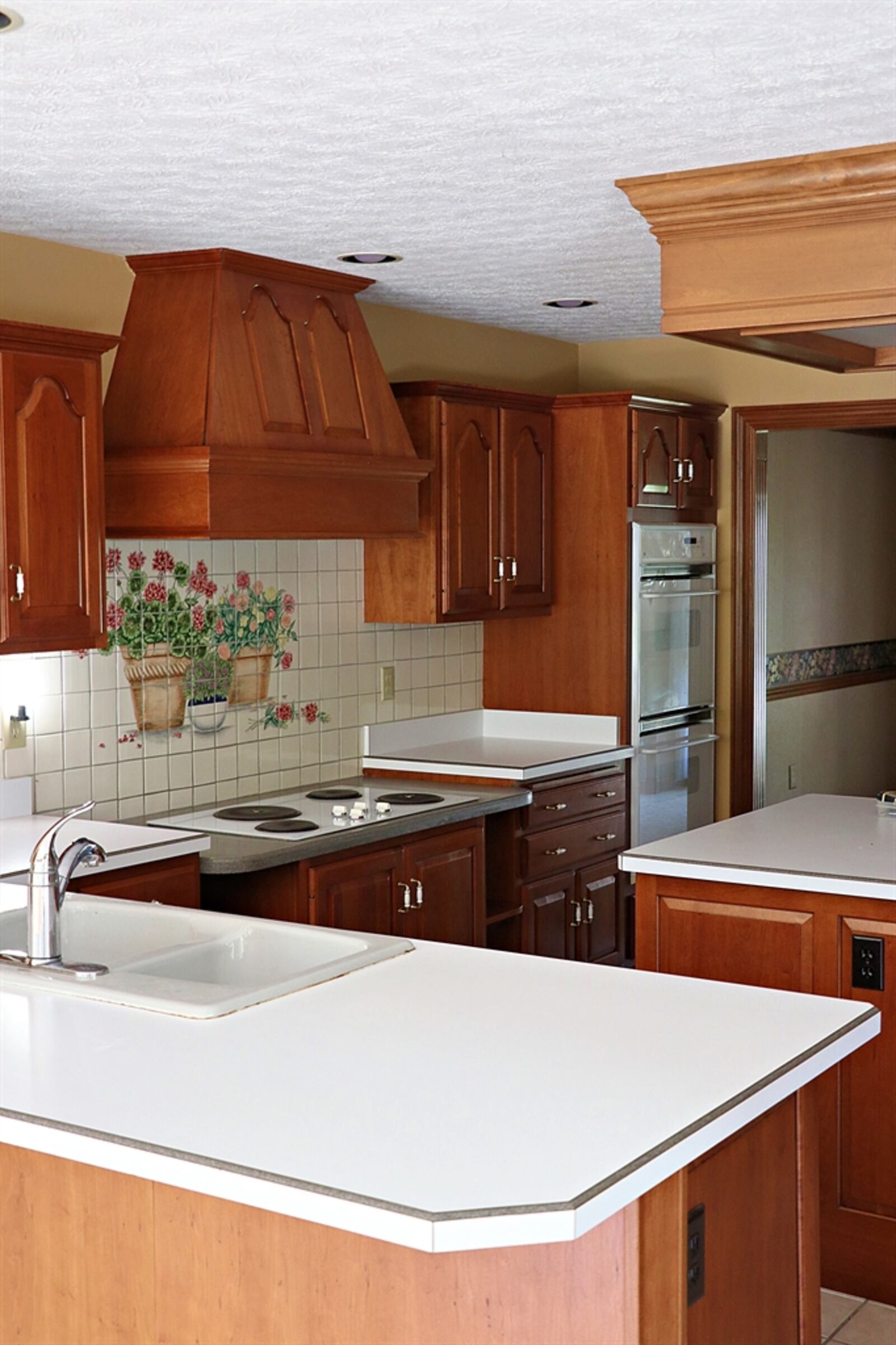 In the kitchen, decorative ceramic tile is above the cooktop and there are double-wall ovens. 