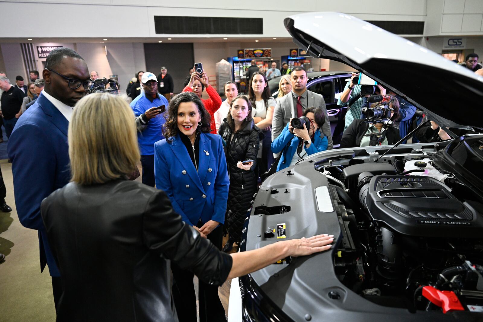 Michigan Gov. Gretchen Whitmer, center, and Lt. Gov. Garlin Gilchrist II, left, are given a tour of a Stellantis vehicle by product specialist Karen Bernard, second from left, at the Detroit Auto Show, Wednesday, Jan. 15, 2025, in Detroit. (AP Photo/Jose Juarez)